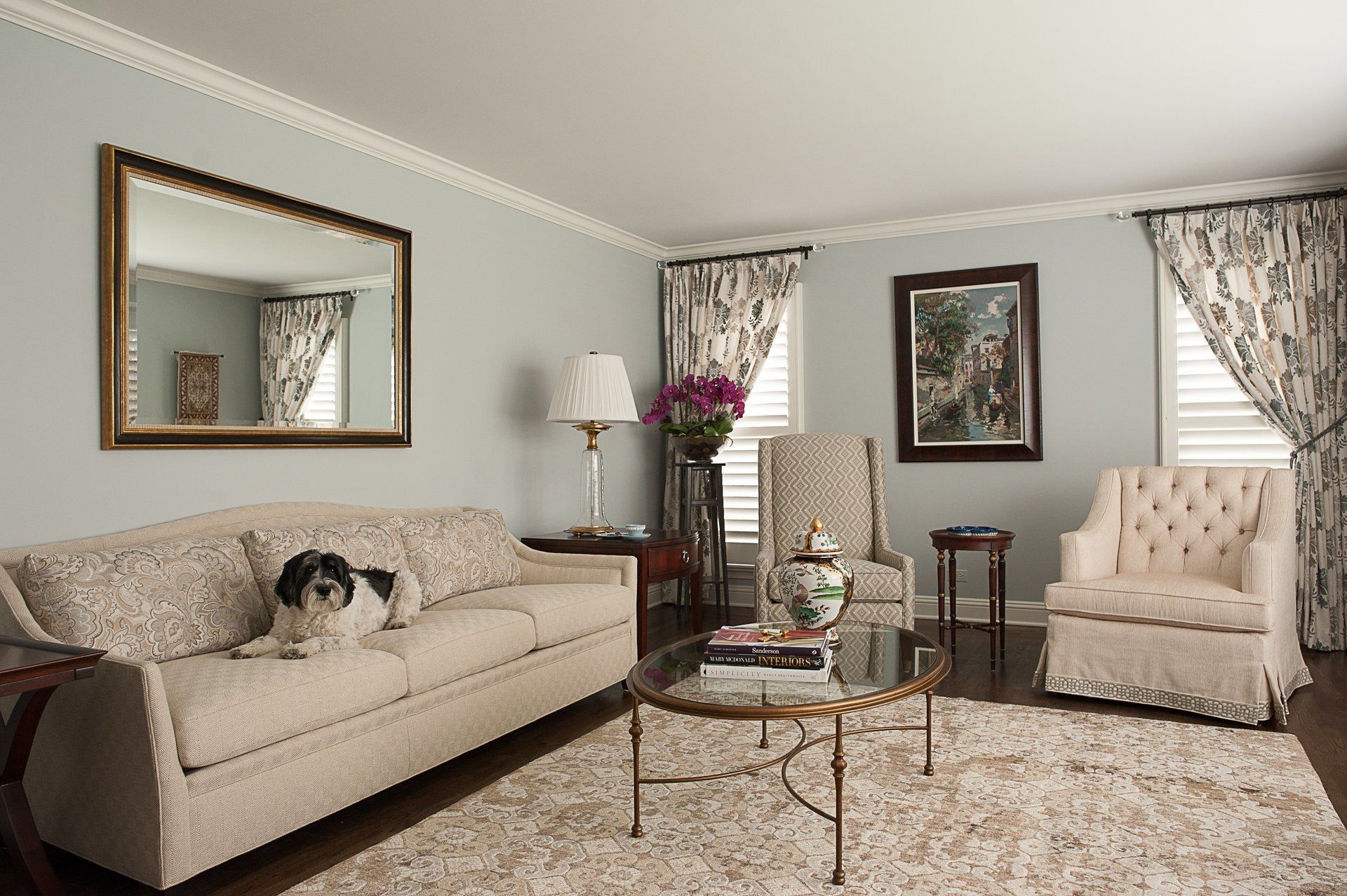 A living room with a couch , chairs , a coffee table and a mirror.