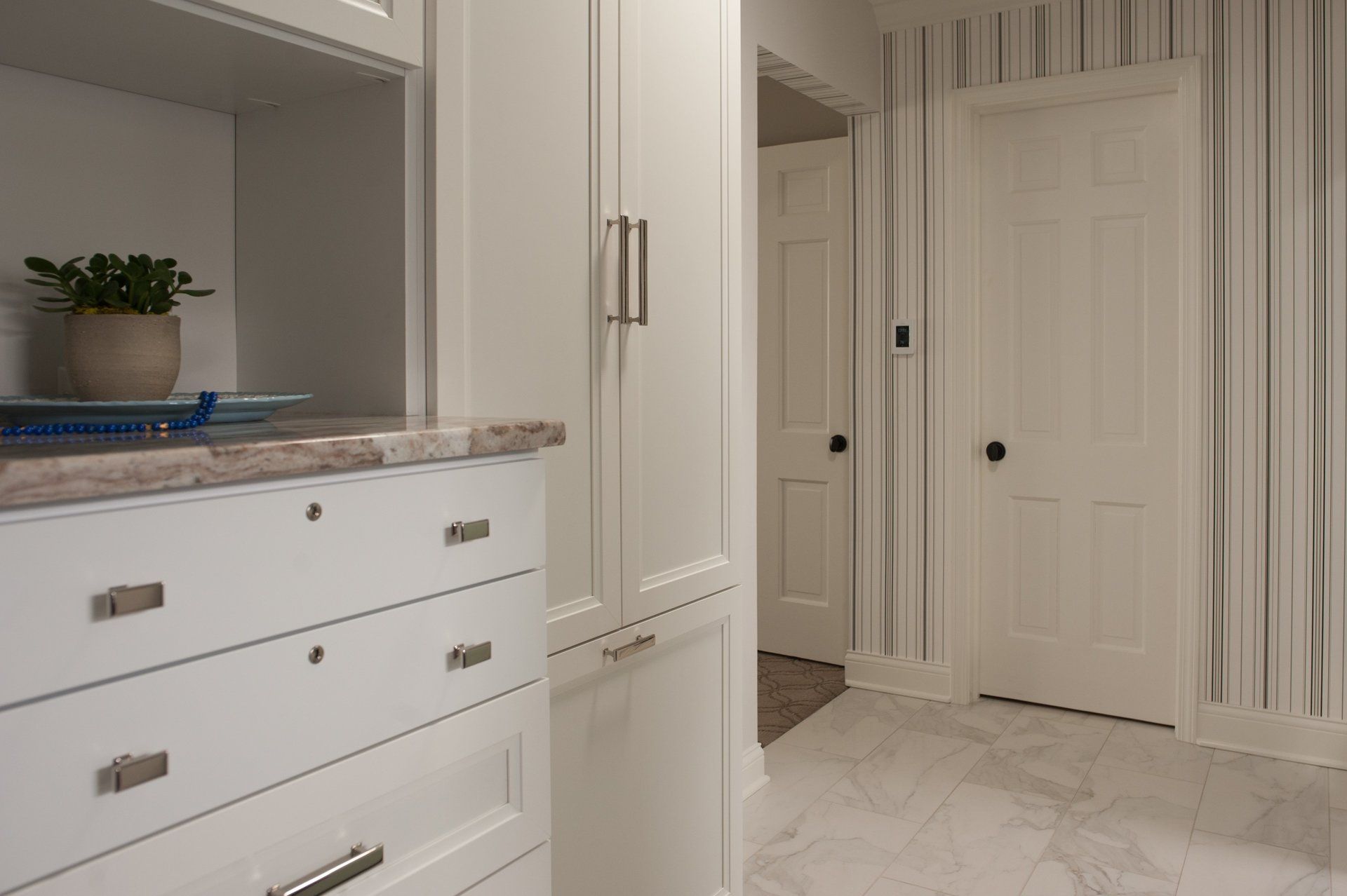 A bathroom with white cabinets , a sink , and a door.