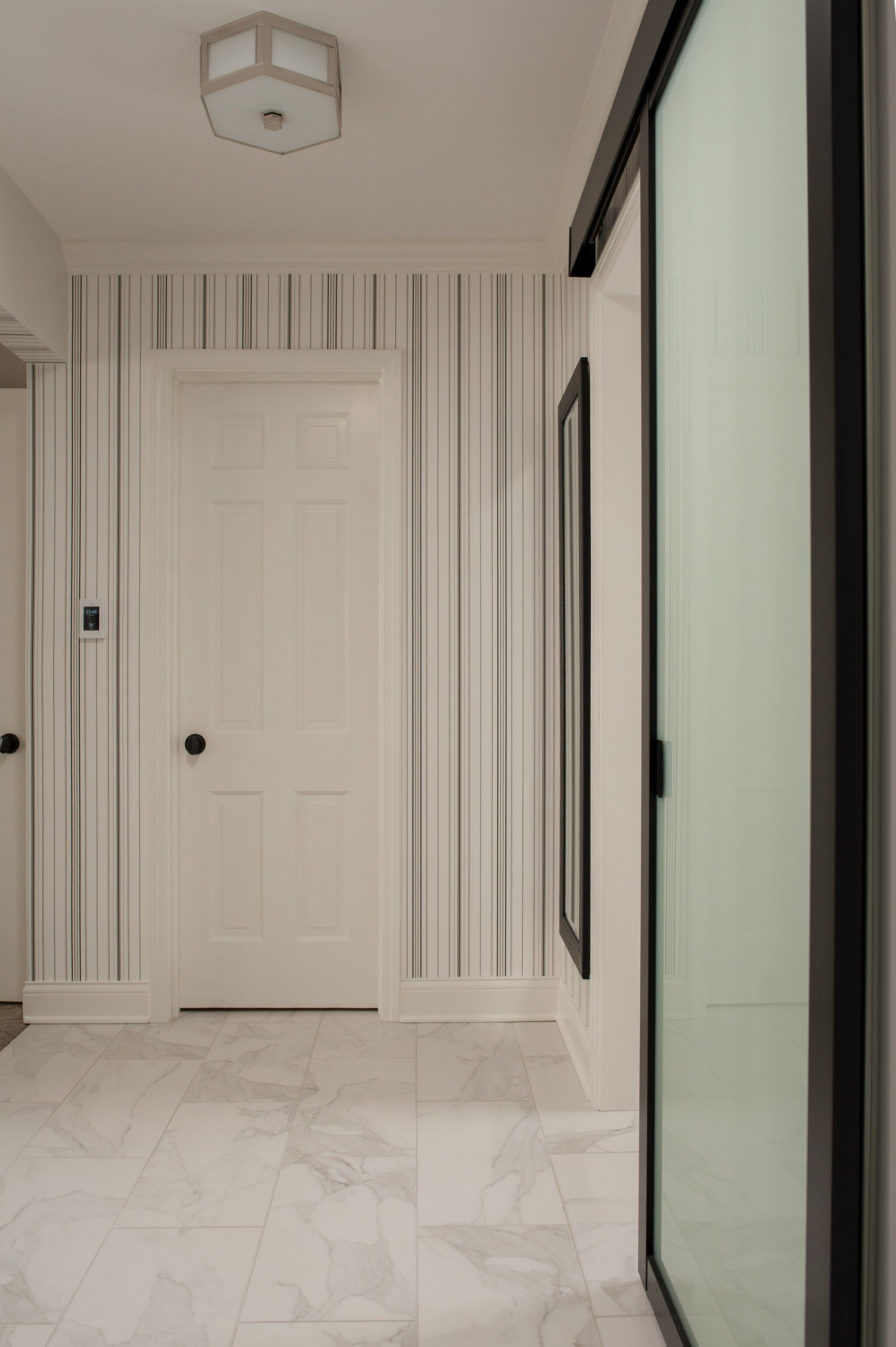A hallway with striped wallpaper on the wall and a door.