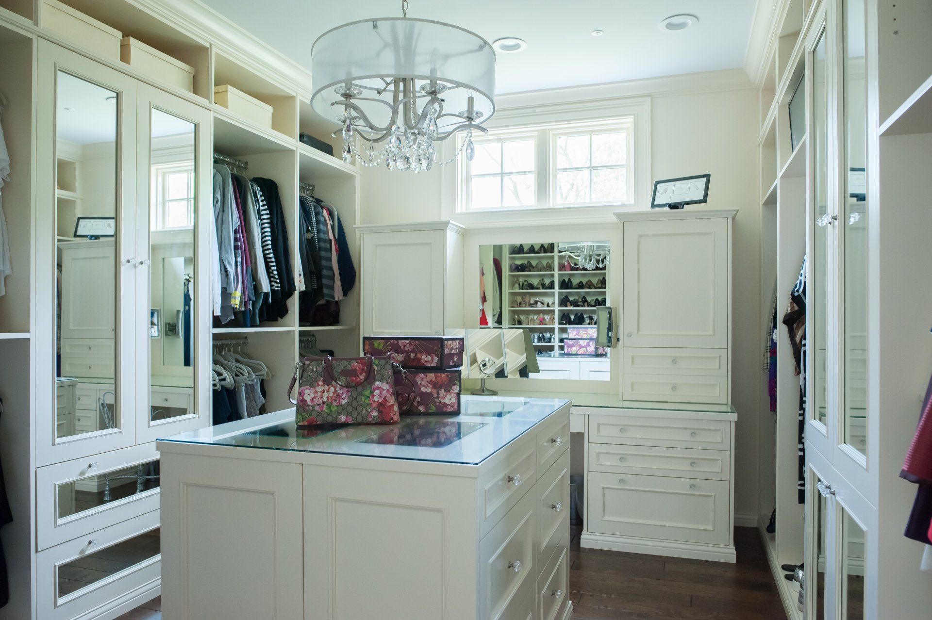 A walk in closet with lots of clothes and a large island in the middle.