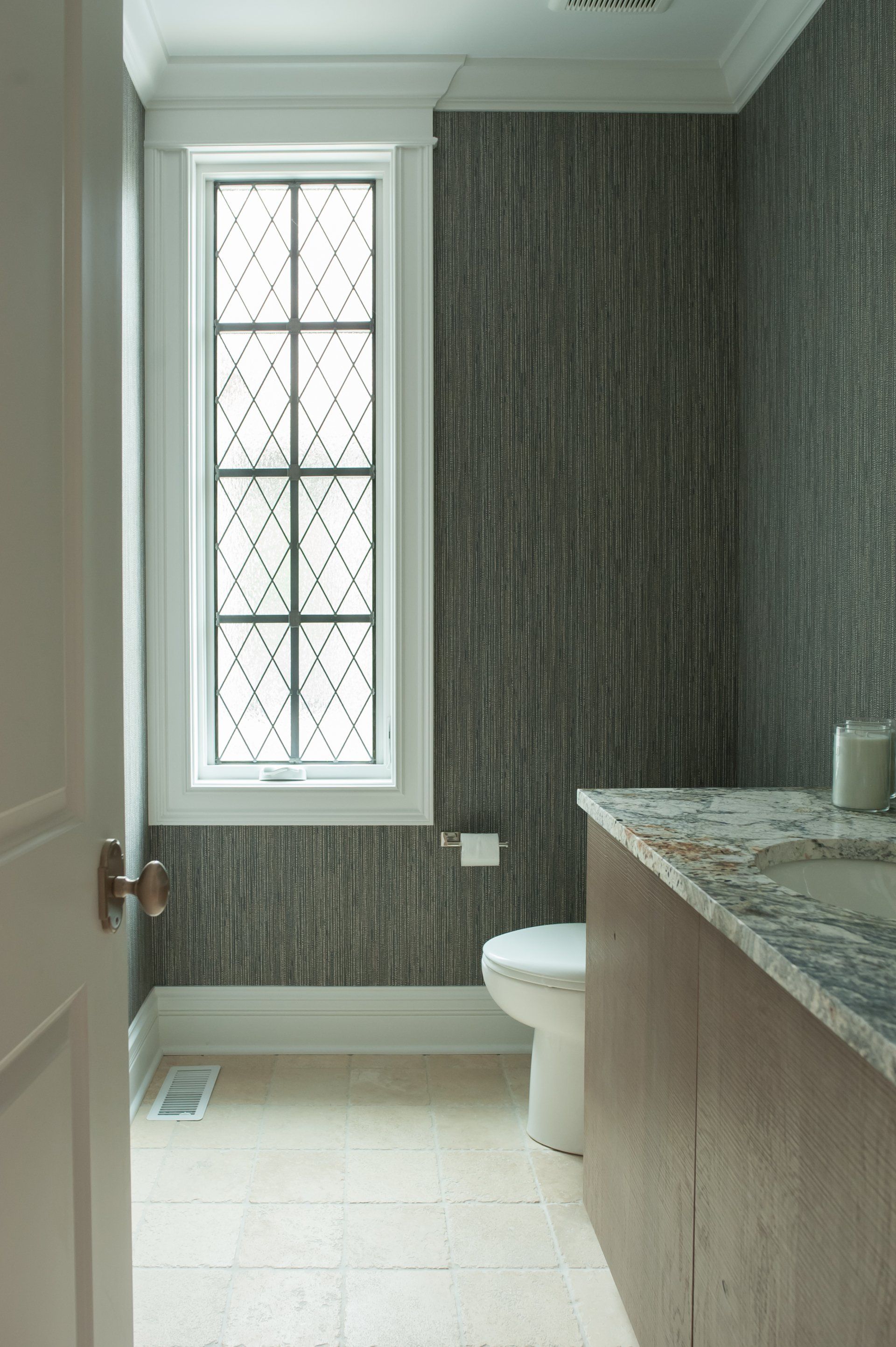A bathroom with a toilet , sink , and window.