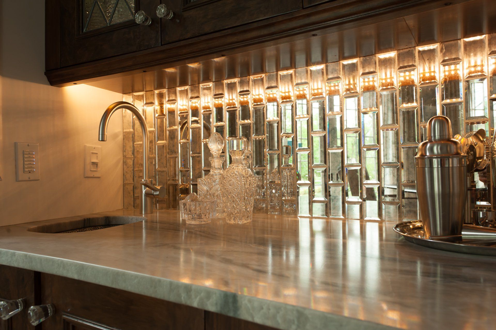 A kitchen counter with a sink and a mirrored backsplash.