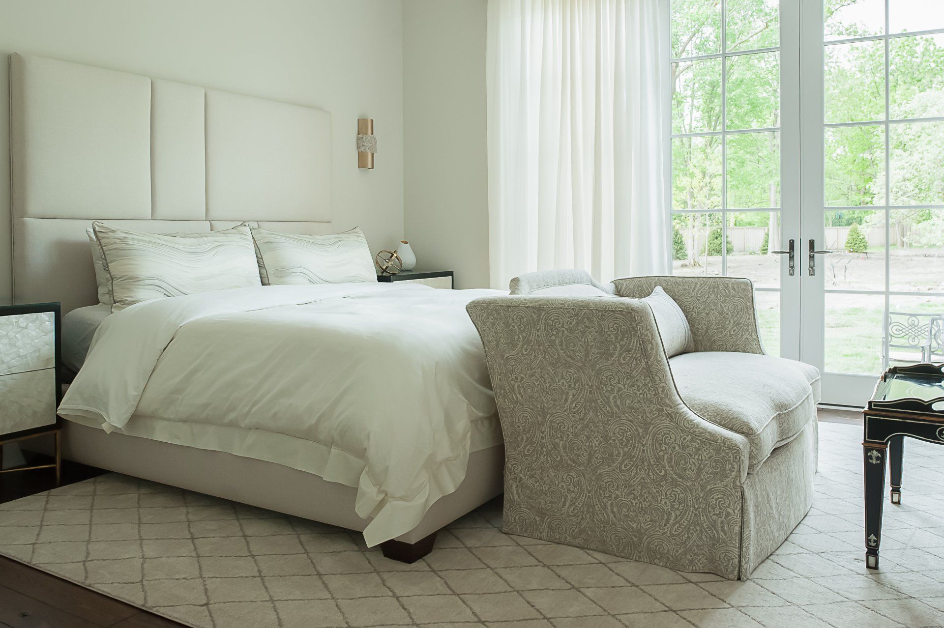 A bedroom with a bed , chair , table and window.