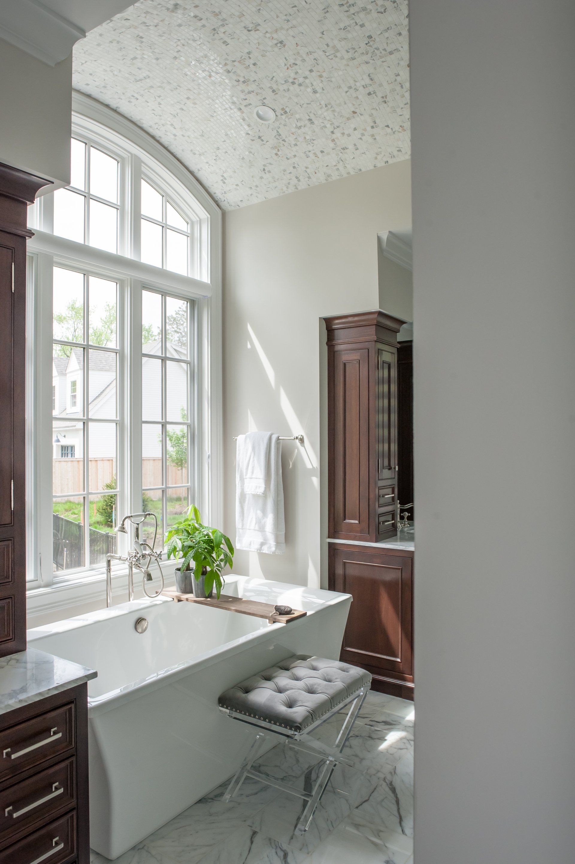 A bathroom with a tub , sink , cabinets and a window.