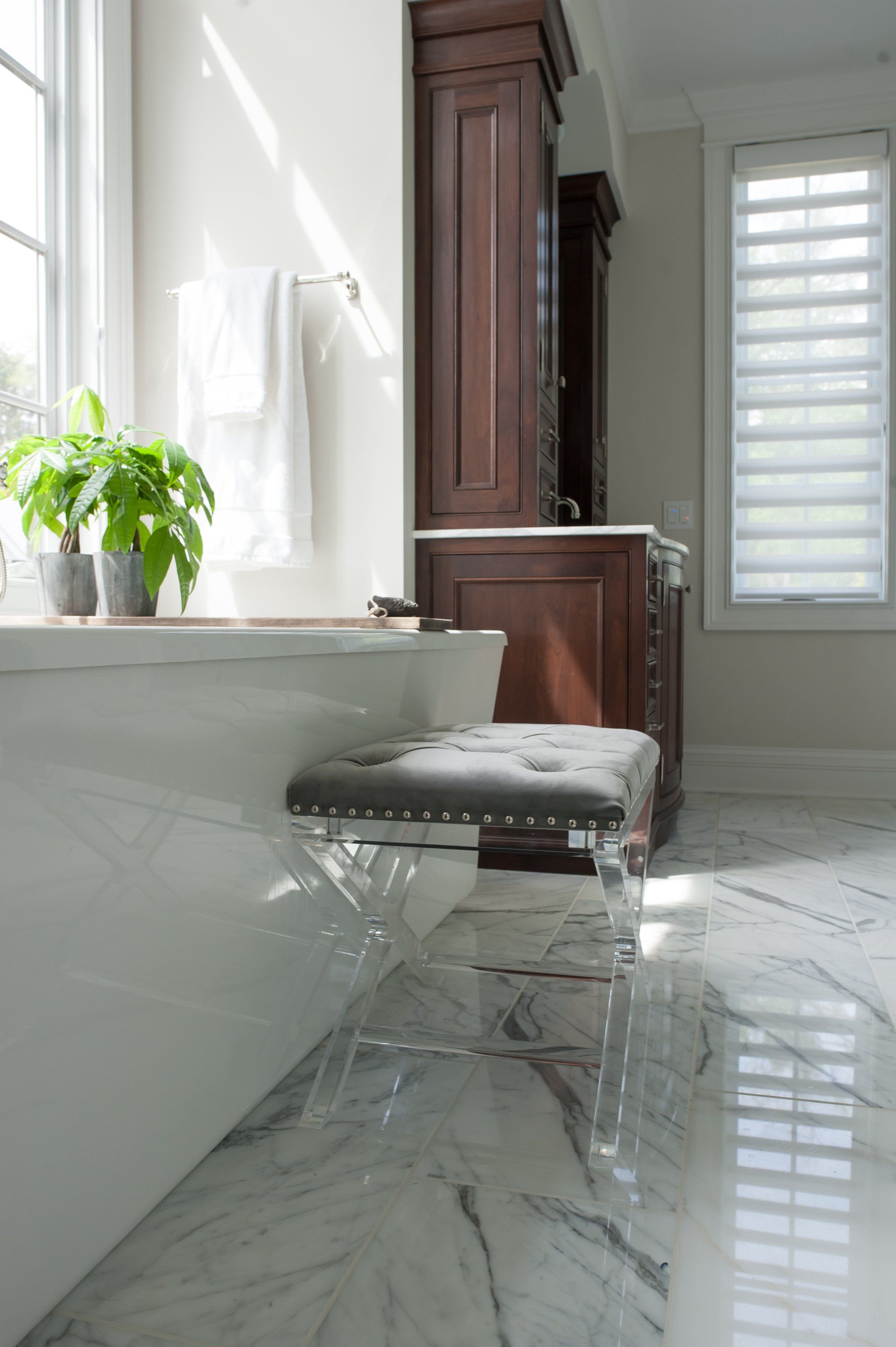 A bathroom with a tub , stool , window and marble floor.
