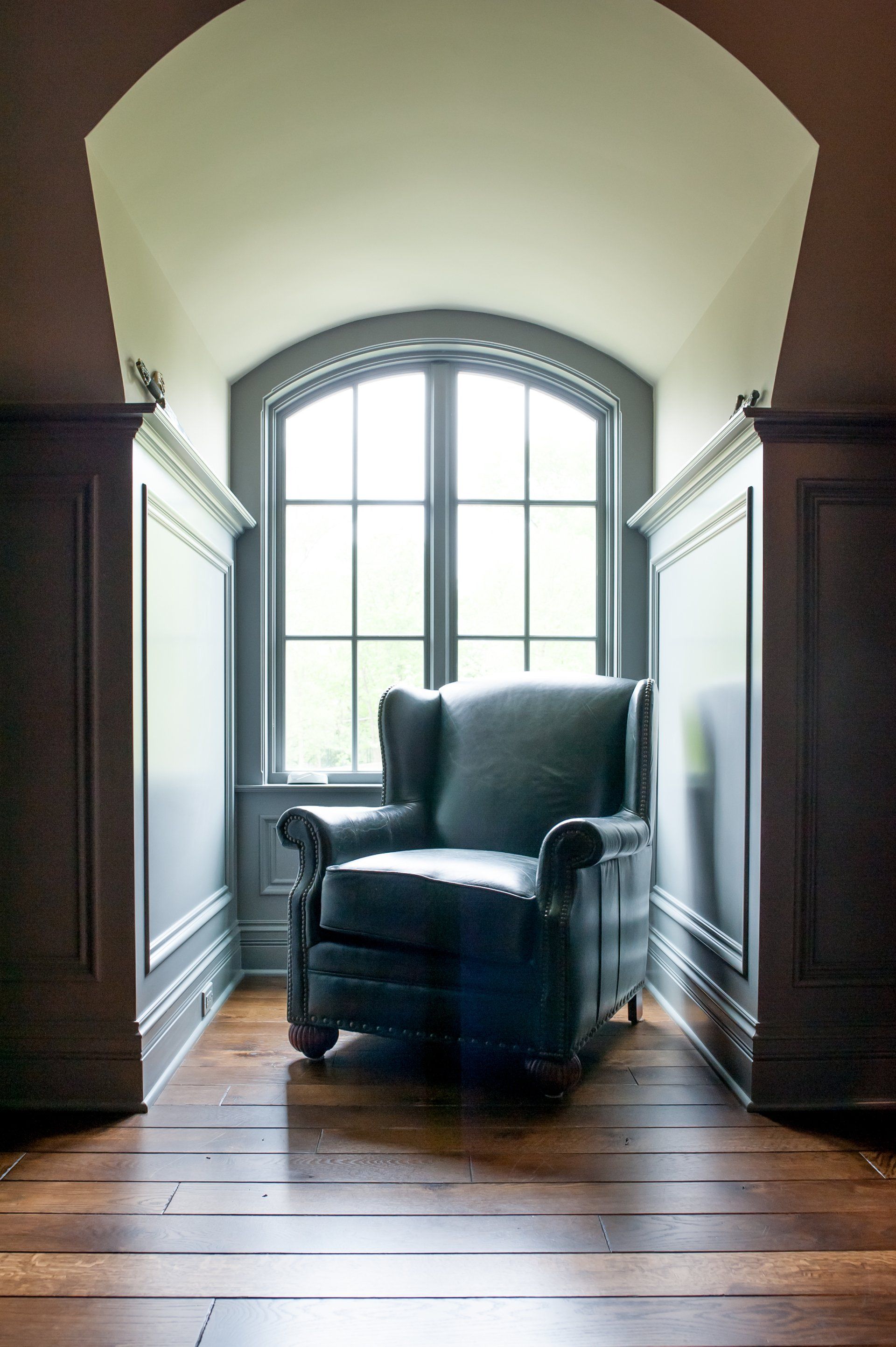 A chair is sitting in a corner of a room next to a window.