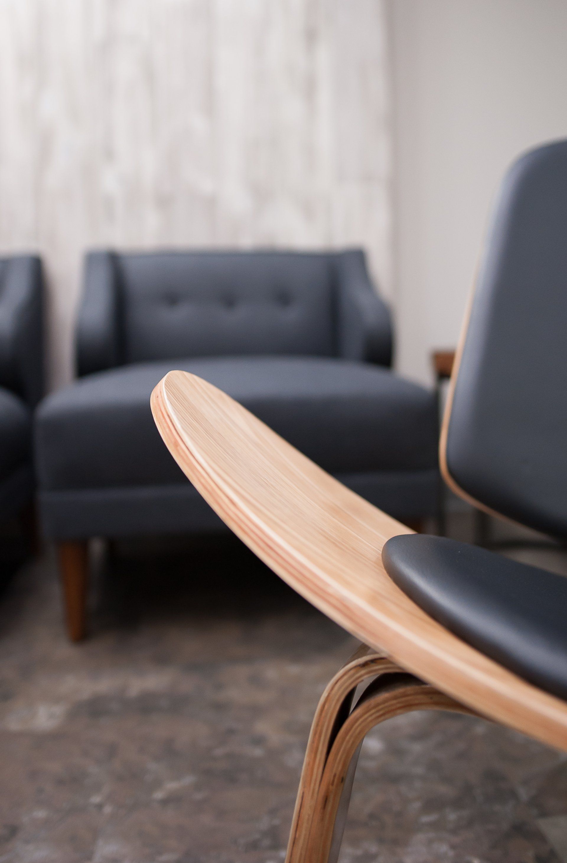 A chair in a living room with a couch in the background
