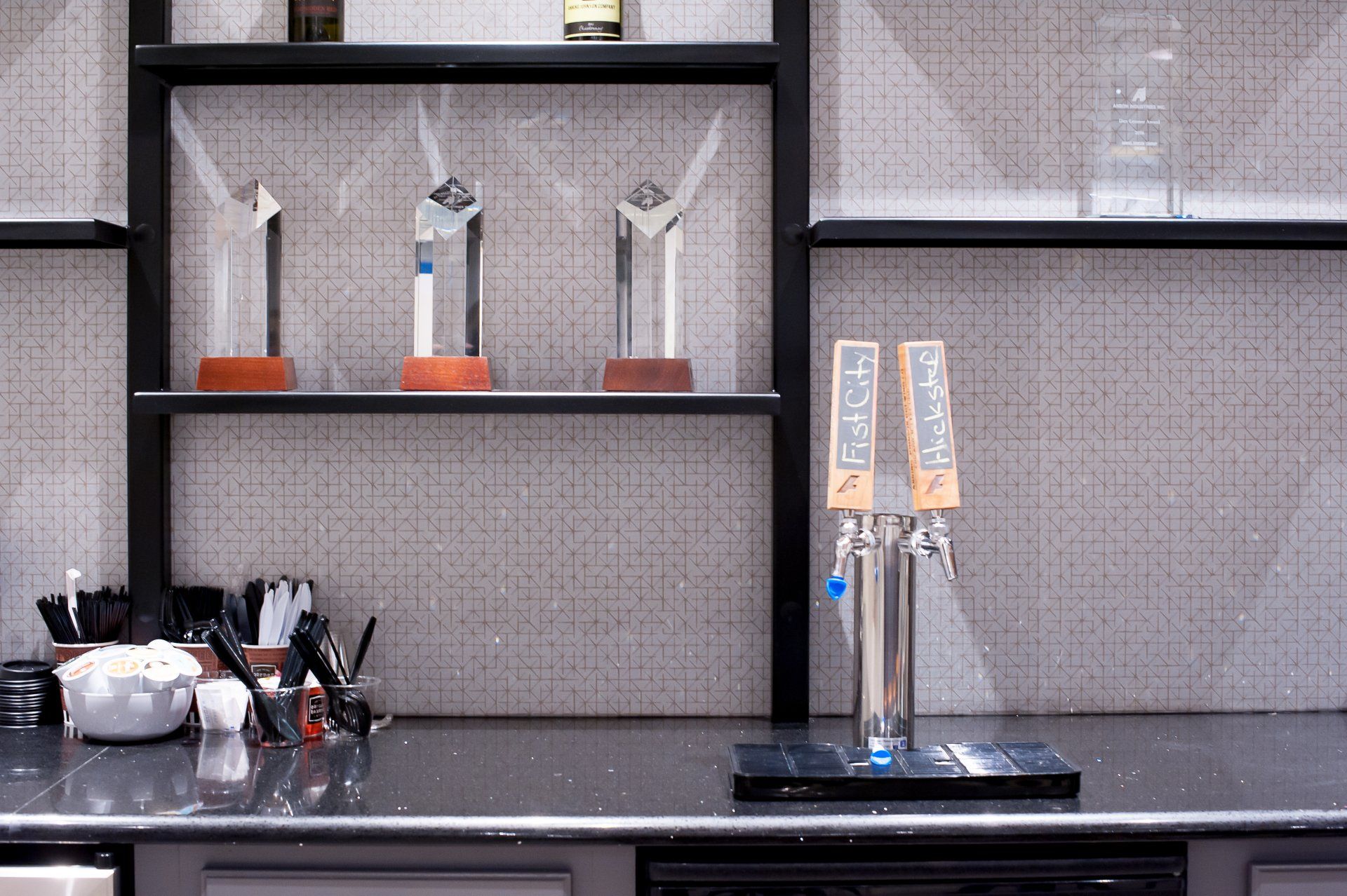 A bar with two taps and shelves with trophies on them