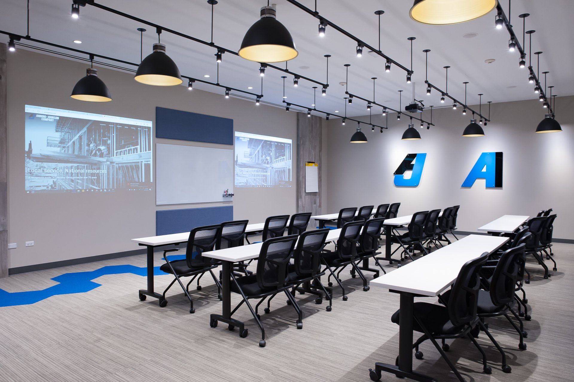 A conference room with tables and chairs and a projector screen