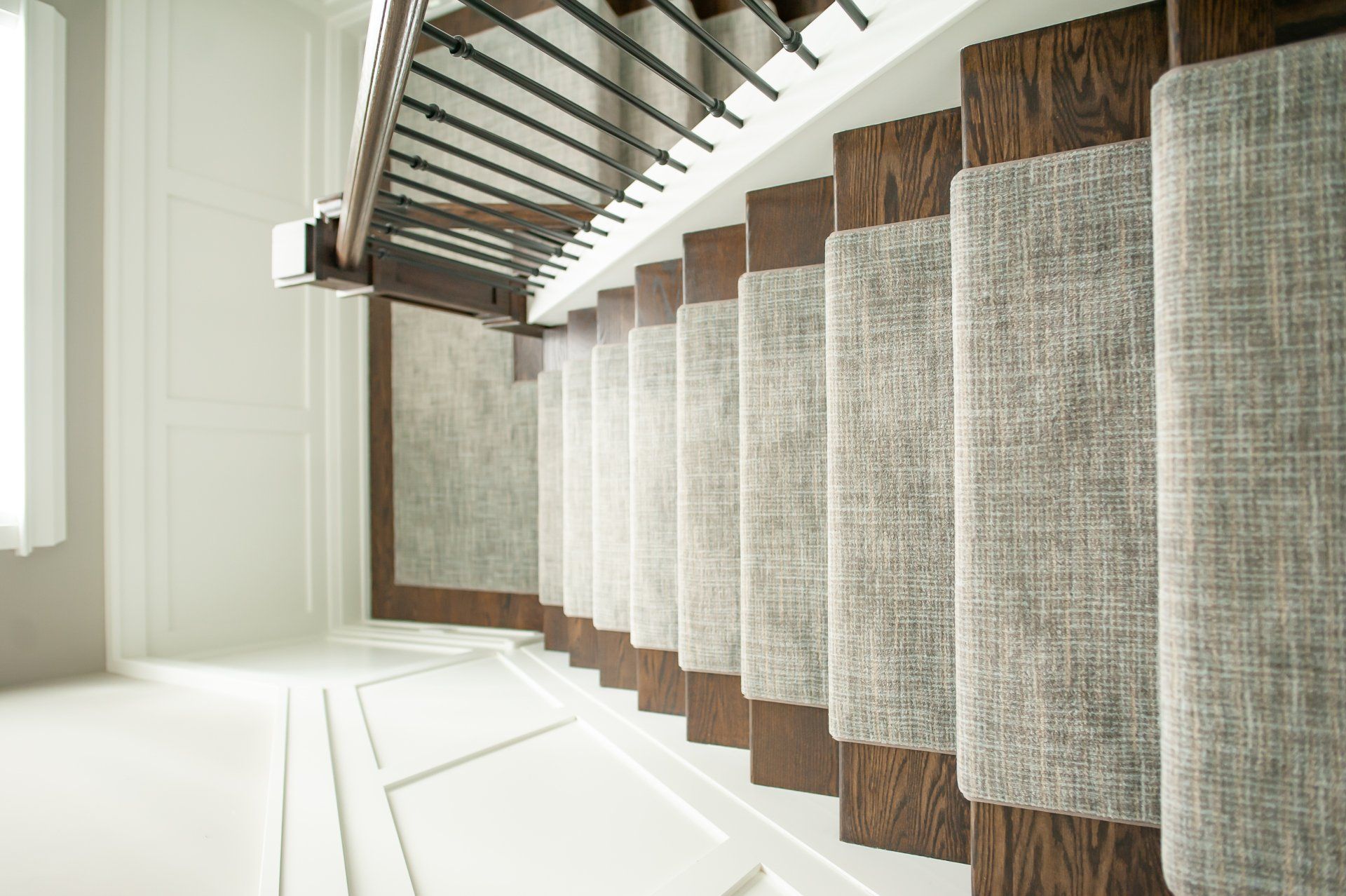 A staircase with a carpet on the steps and a wooden railing.