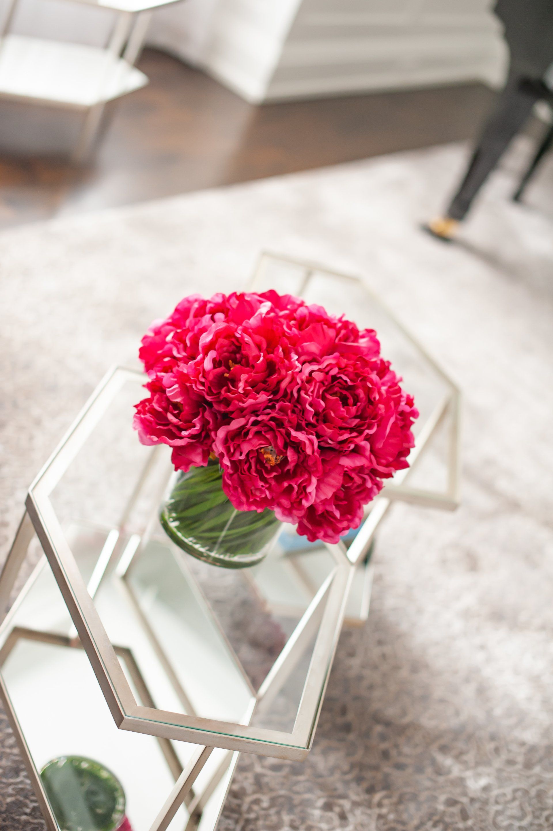 A vase of pink flowers is sitting on a glass coffee table.