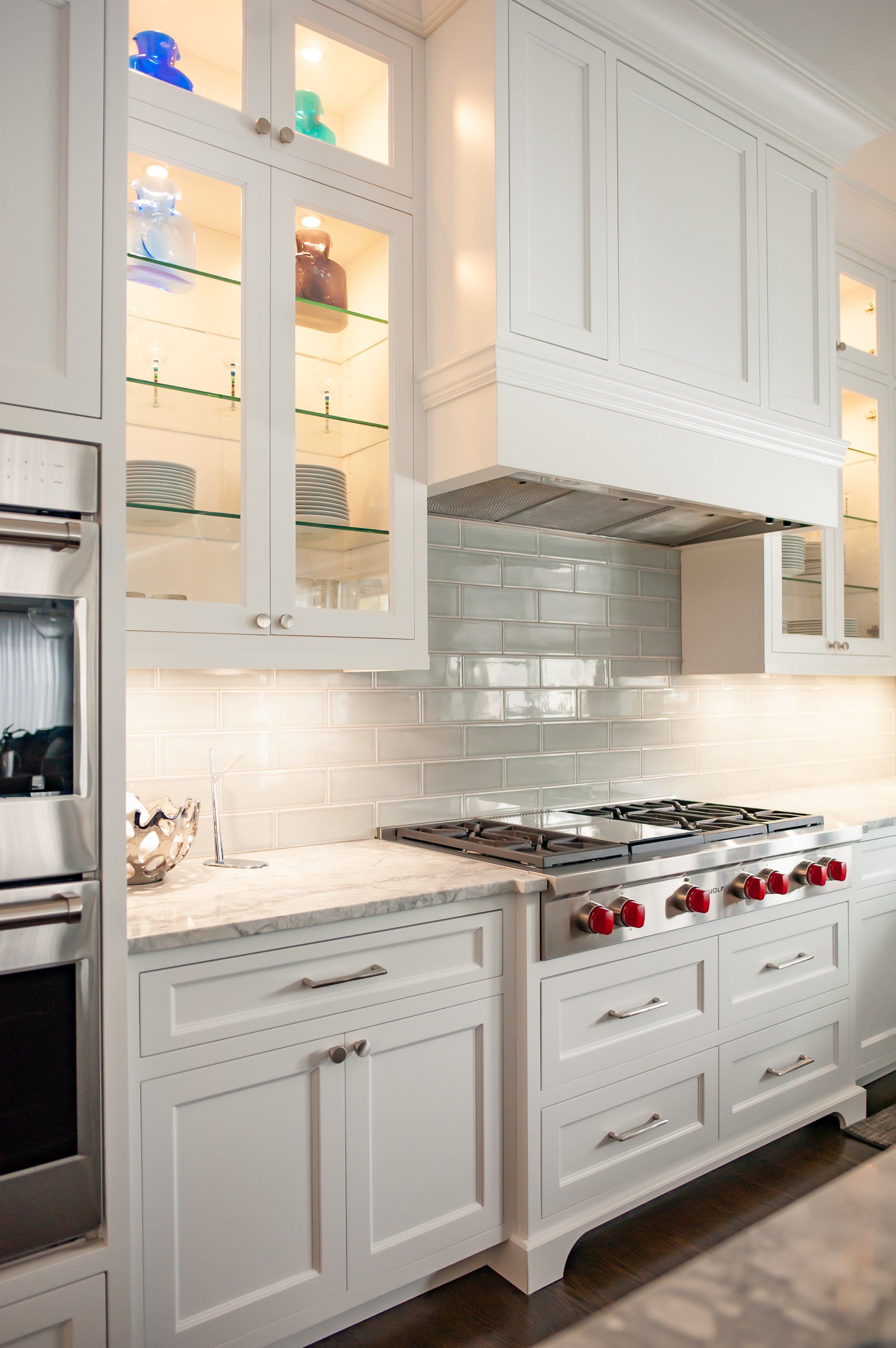 A kitchen with white cabinets , stainless steel appliances , and a stove top oven.