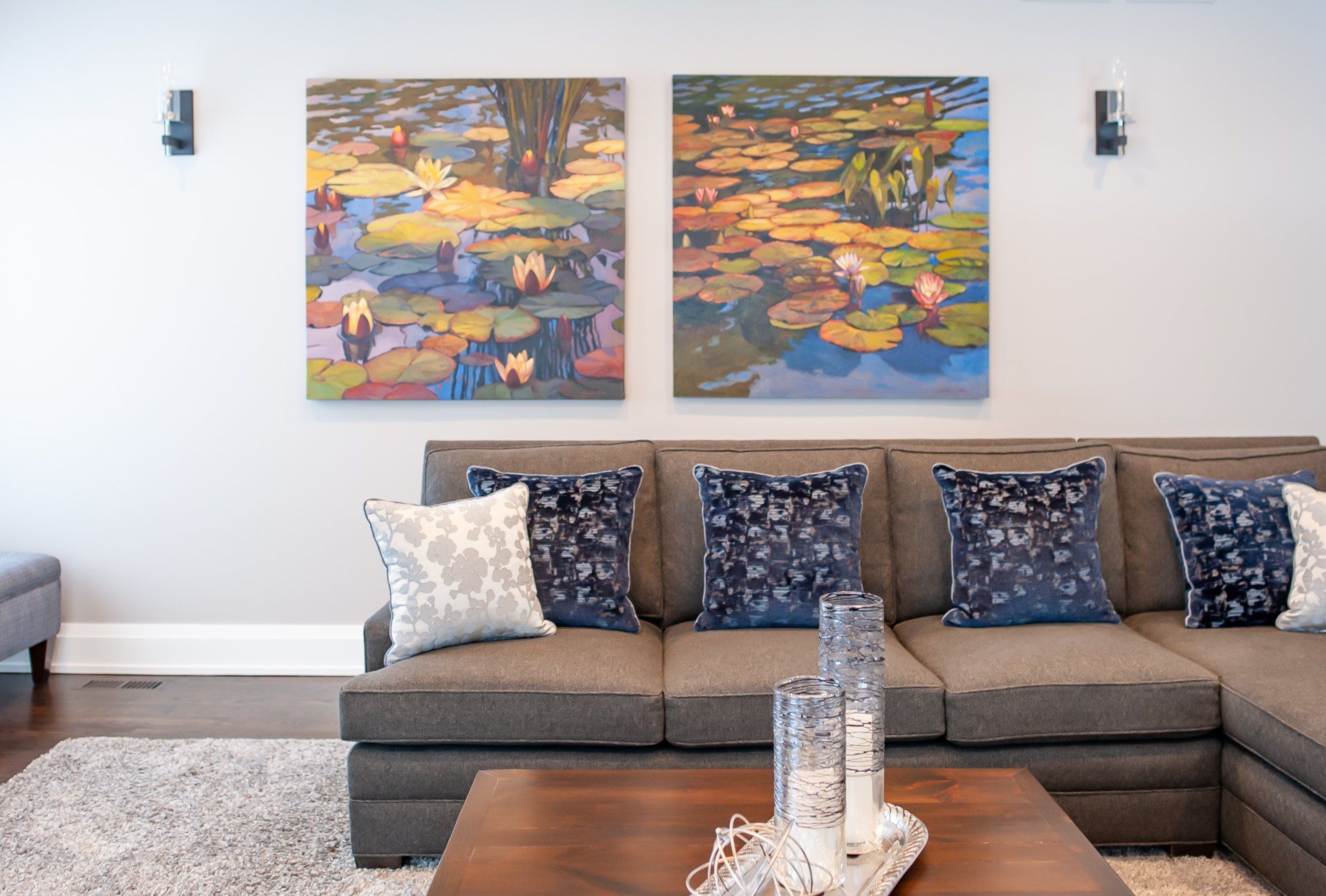 A living room with a couch , coffee table , and two paintings on the wall.