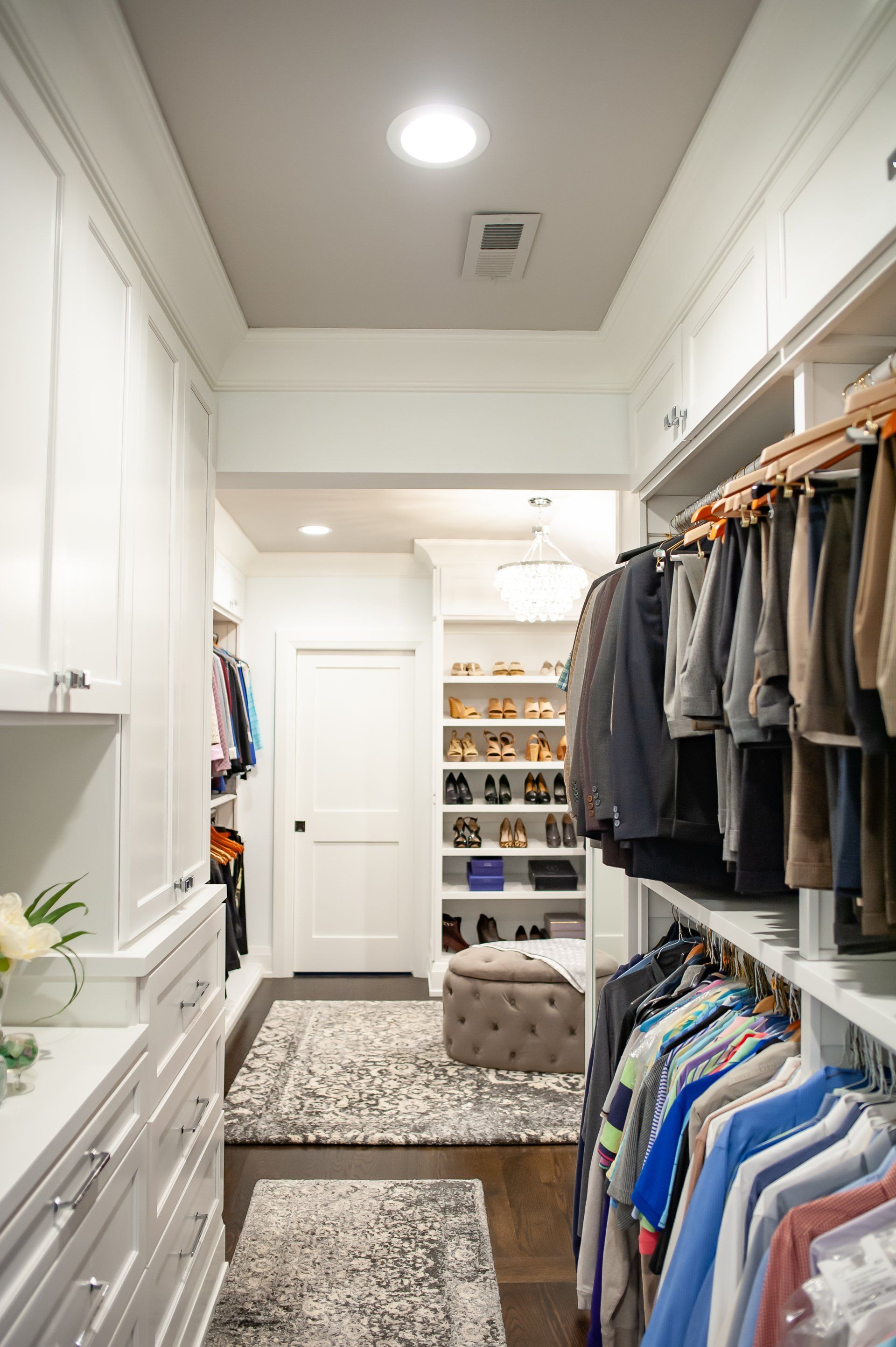 A walk in closet filled with lots of clothes and shoes.