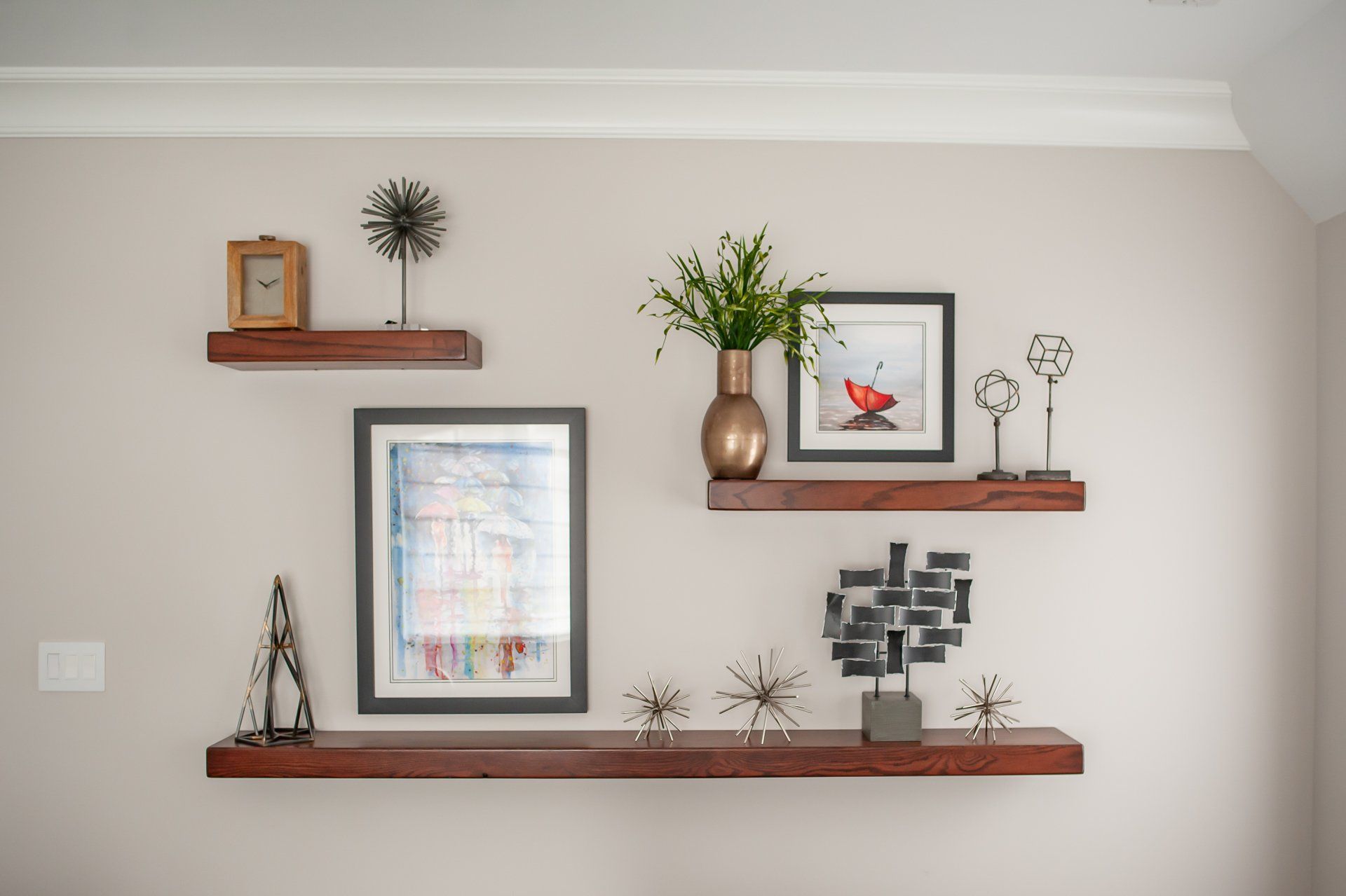 A wall with three shelves filled with pictures and decorations.