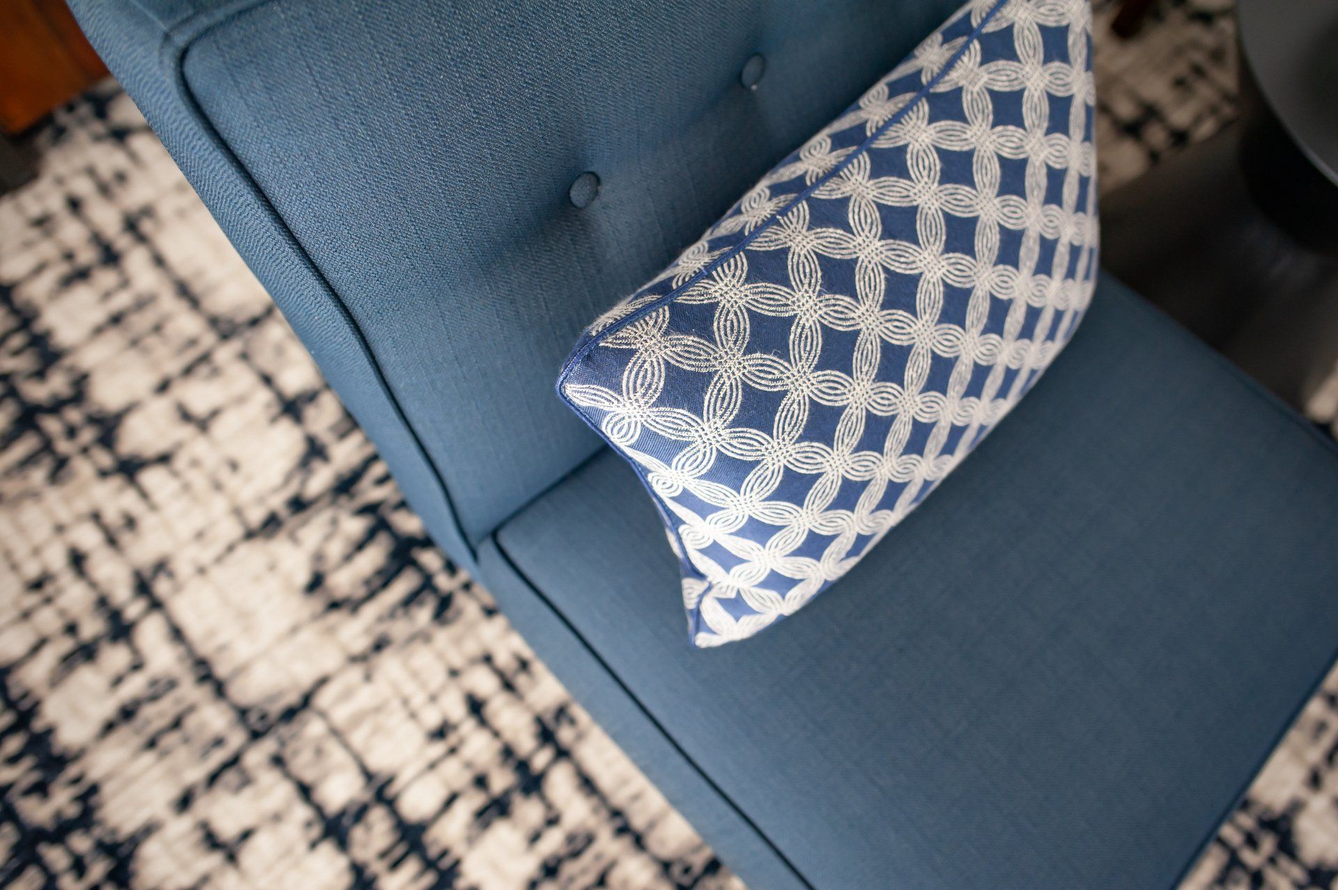 A blue couch with a blue and white pillow on it