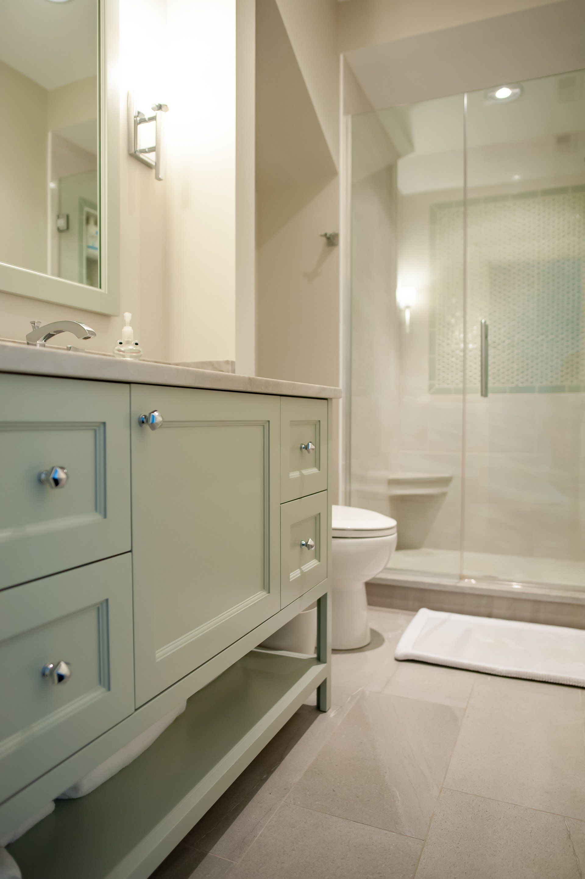 A bathroom with a toilet , sink , mirror and walk in shower.