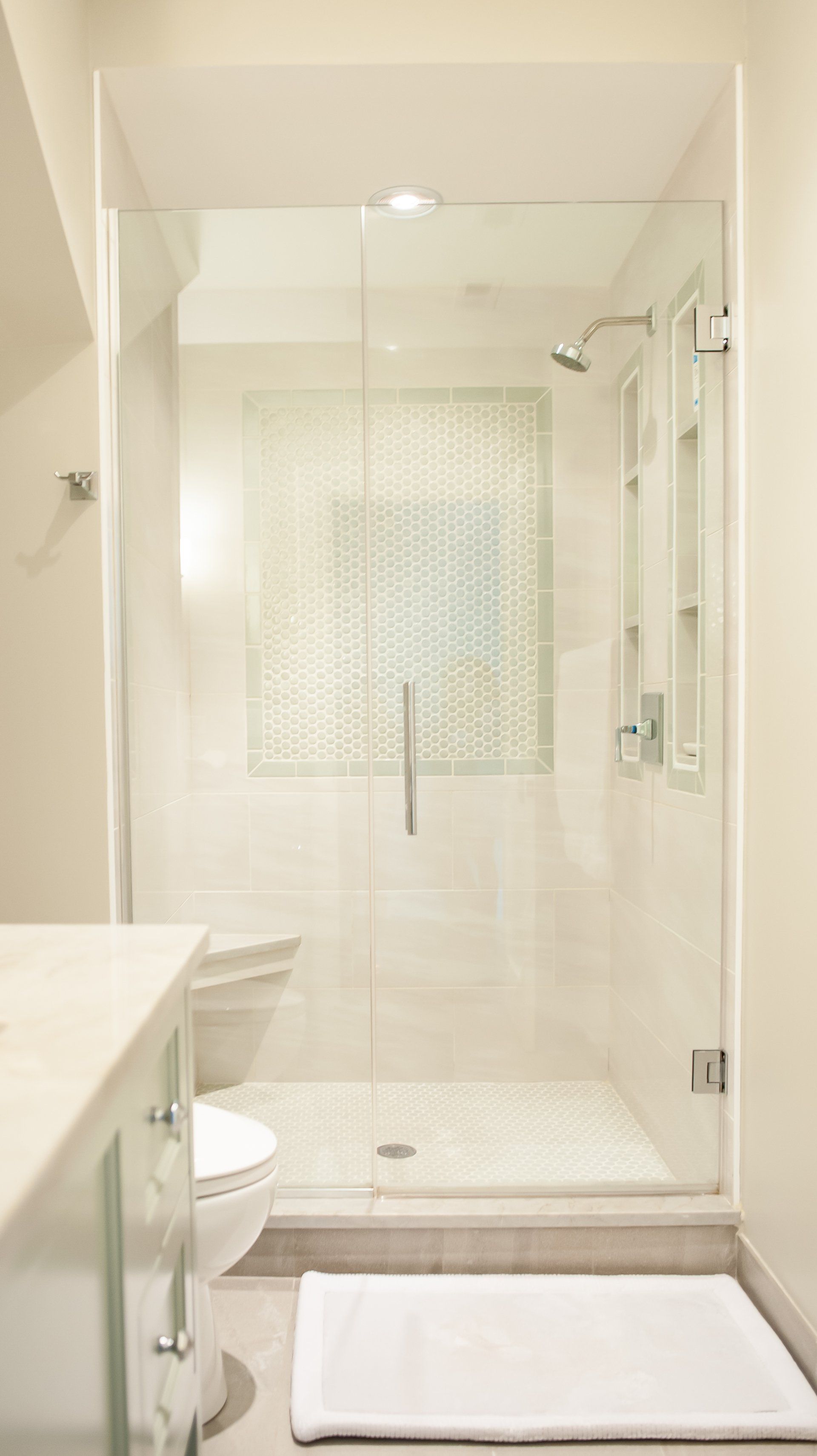 A bathroom with a toilet and a walk in shower with a glass door.