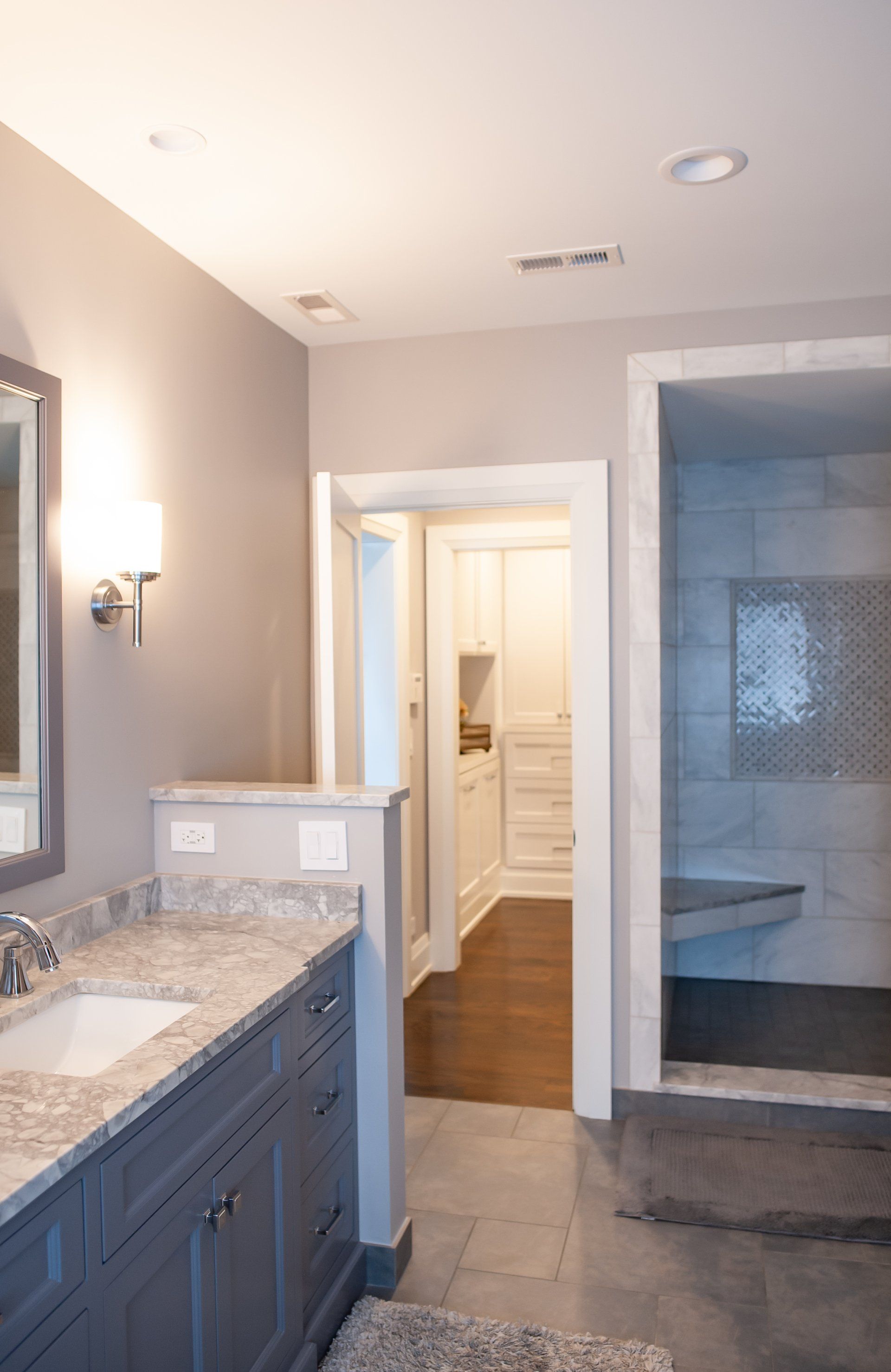 A bathroom with a sink , mirror and walk in shower.