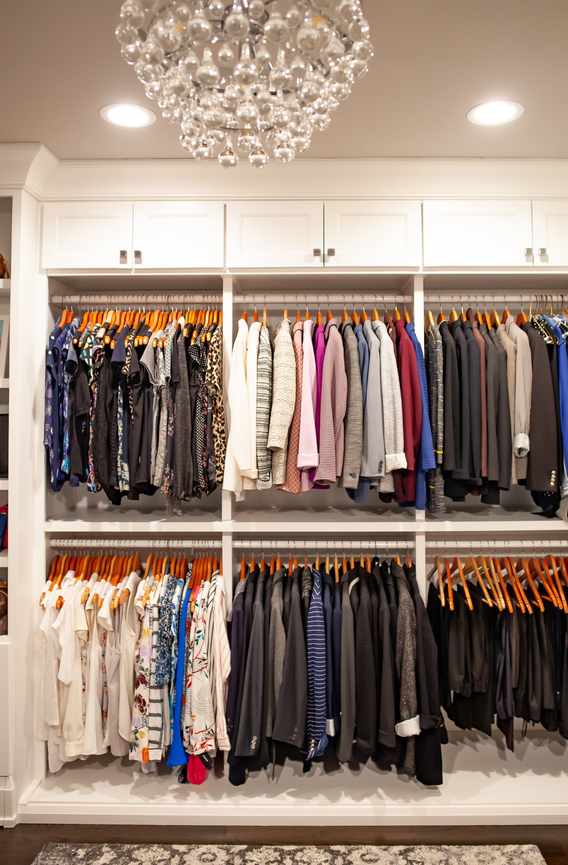 A closet filled with lots of clothes and a chandelier hanging from the ceiling.