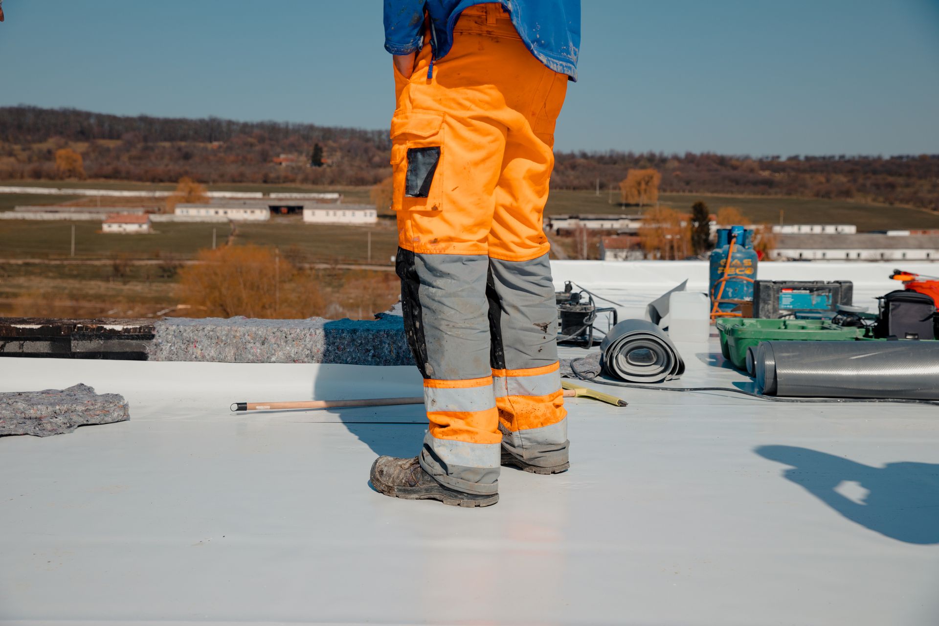 A man is standing on top of a white roof.