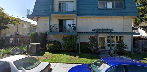A blue car is parked in front of a building.
