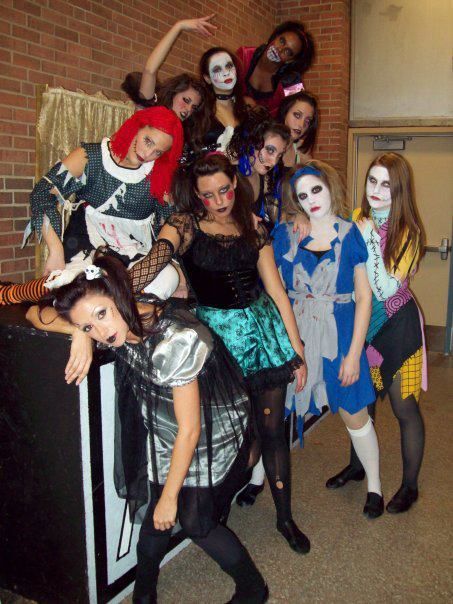 Group of costumed figures; Halloween theme, mostly zombies. Figures dressed in torn attire, pale makeup, and various poses.