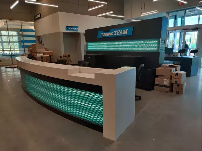 Empty retail counter with teal-lit front and stacked boxes in a store workspace