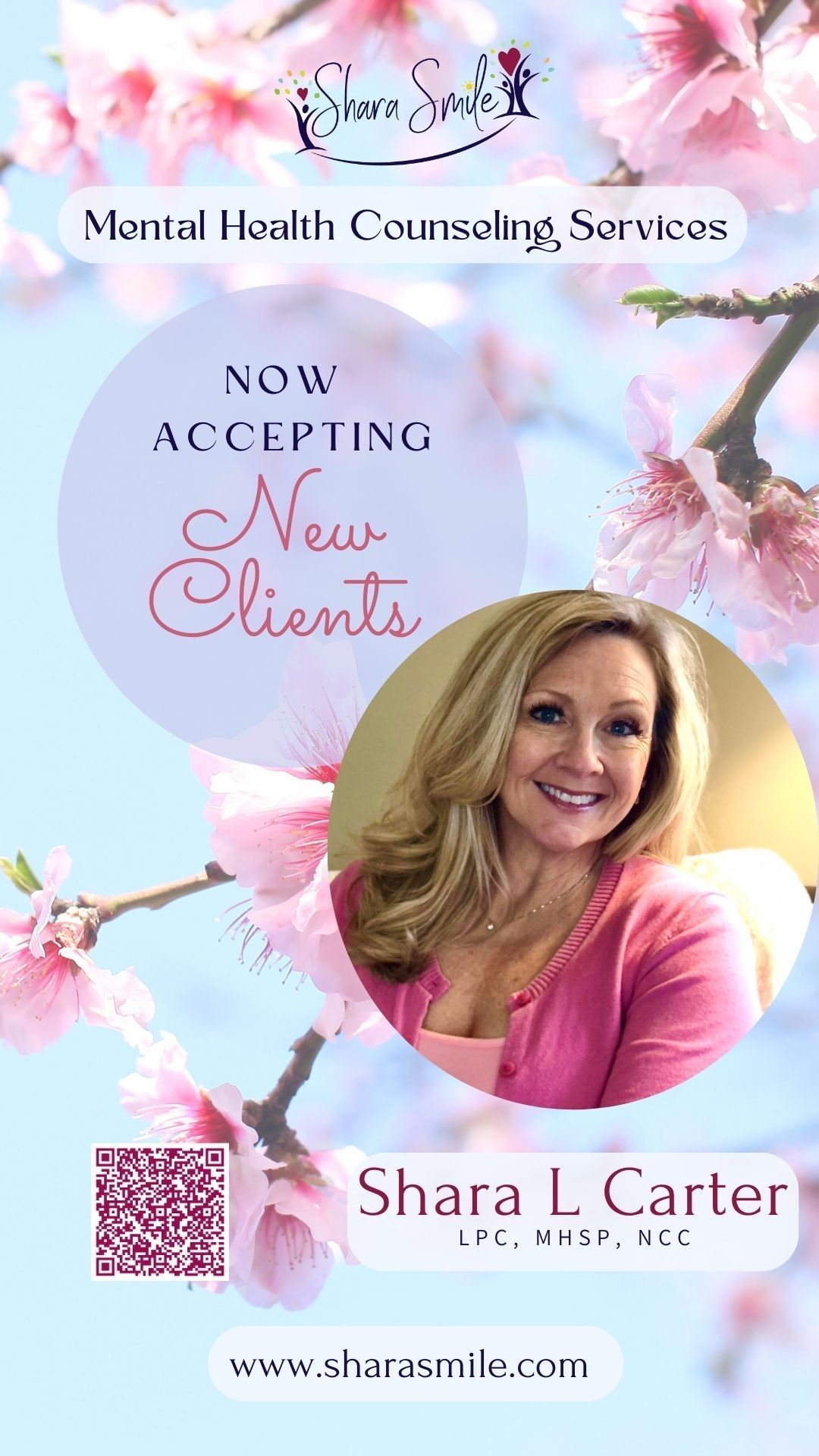 A woman in a pink shirt is standing in front of a cherry blossom tree.