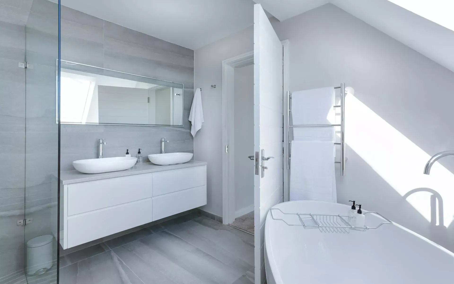 Modern, bright white bathroom with a floating vanity, soaking tub, and open doorway.