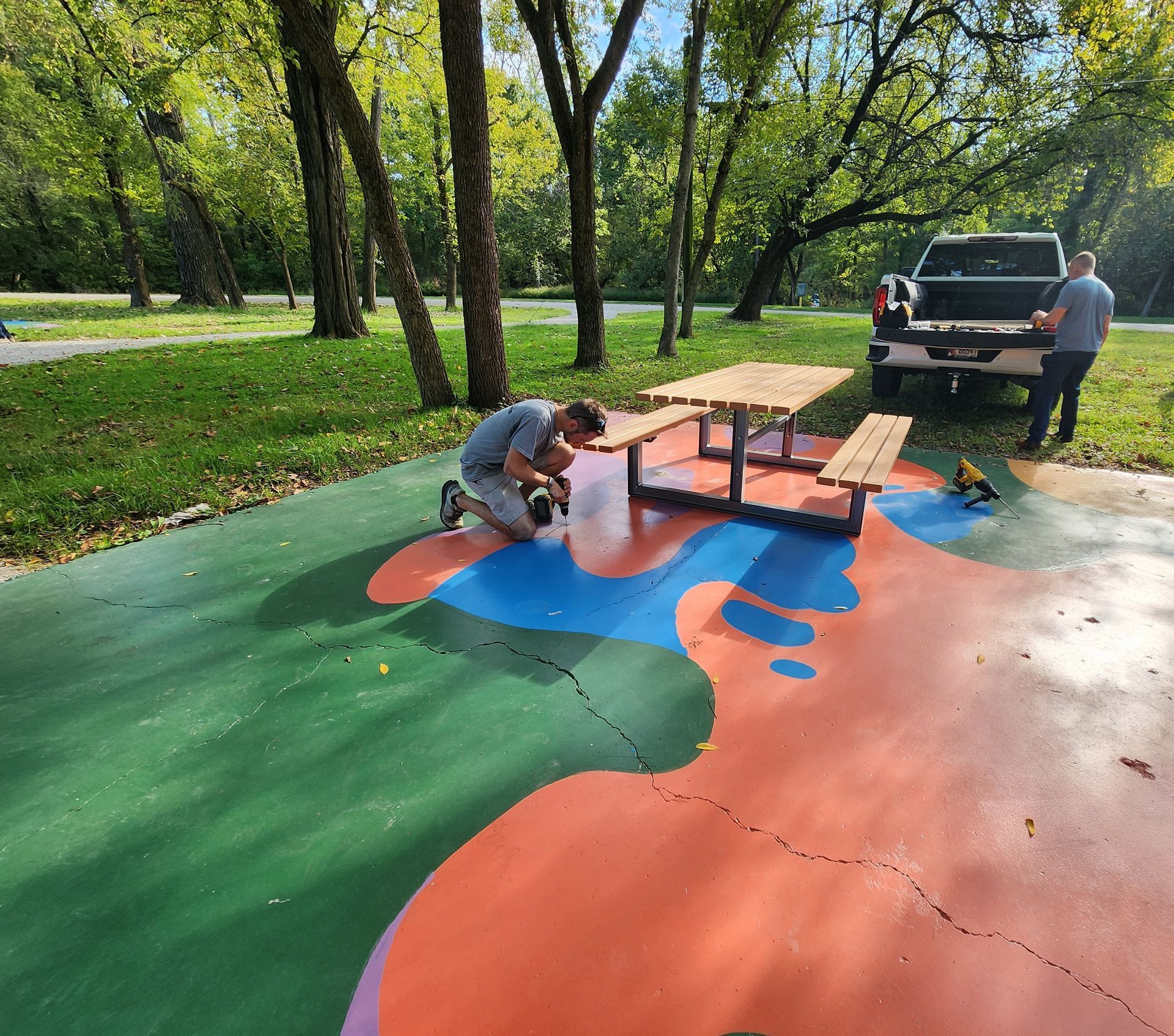 A man paints a picnic table in a park