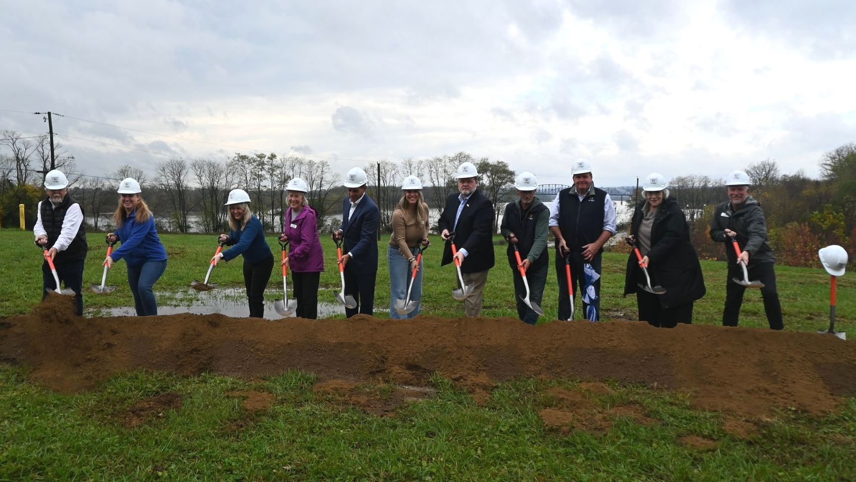 A group of people are digging in a field with shovels.