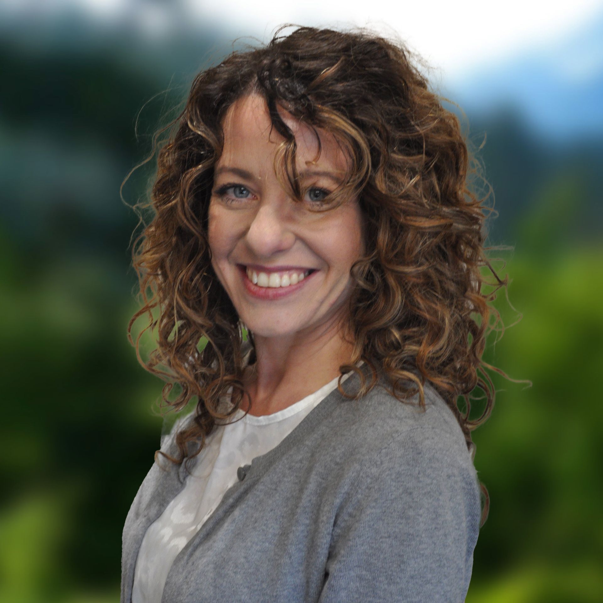 Lauren Johnson wearing a blue sweater, set against a blurred green background.