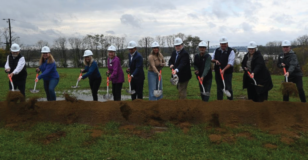 A group of people are digging in a field with shovels. Ground breaking of Origin Park's Event Center.