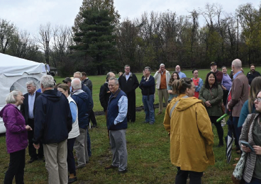 A group of people are standing in a field talking to each other.