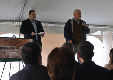 Two men standing in front of a group of people holding microphones