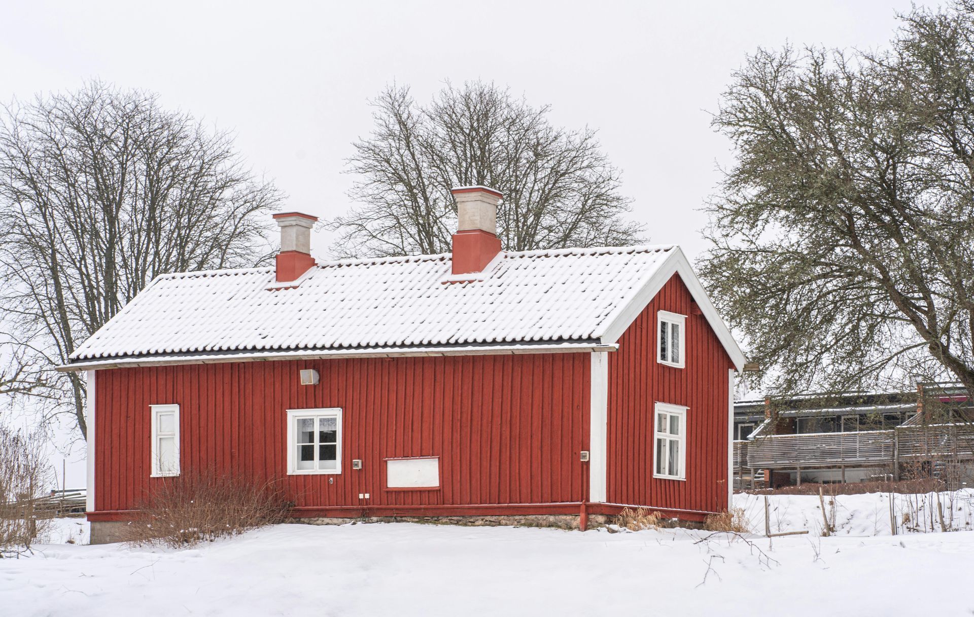 Red wooden cottage with a snow-covered roof and surrounding snow in State College