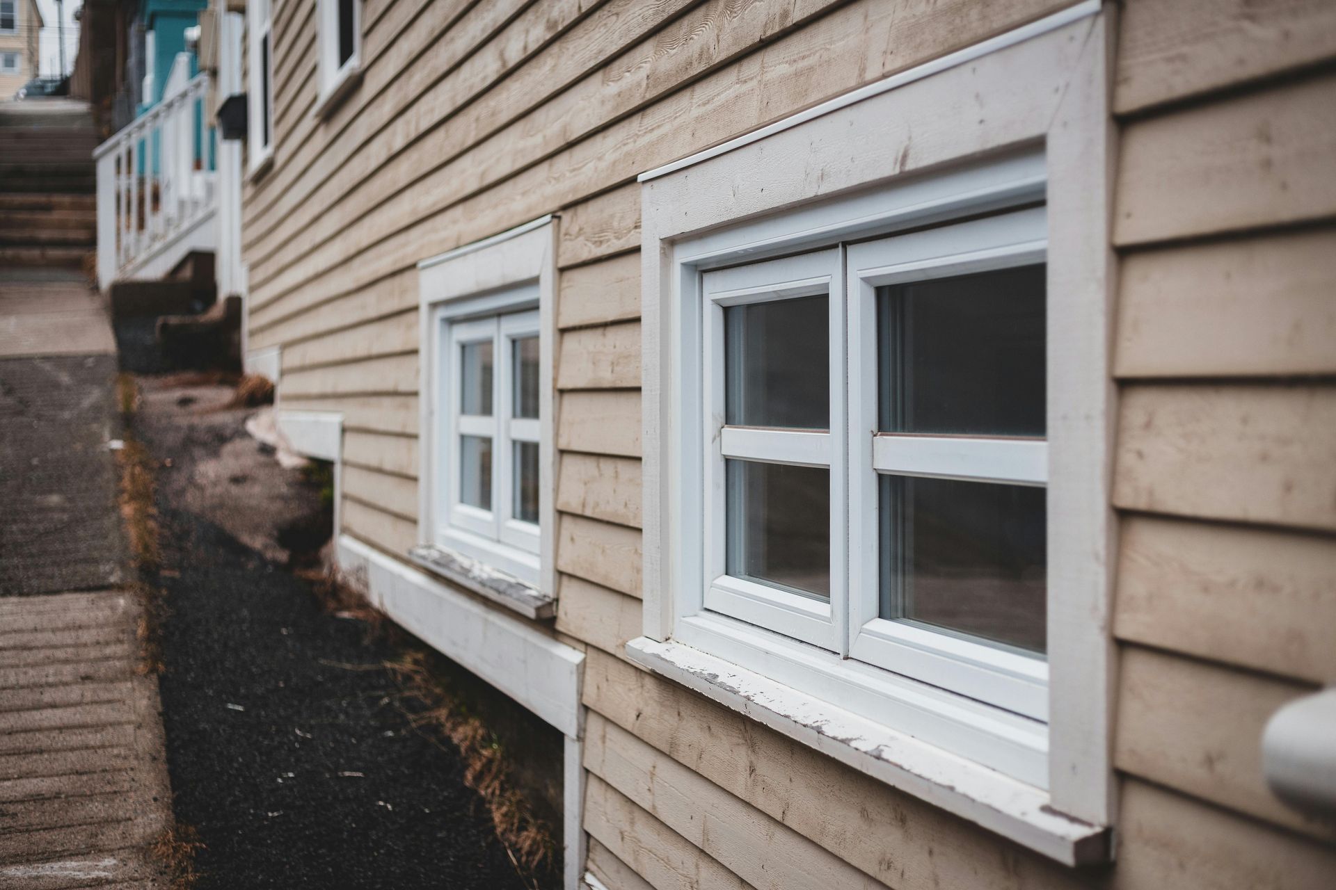 Two white-framed windows on a light-colored wooden house in State College.