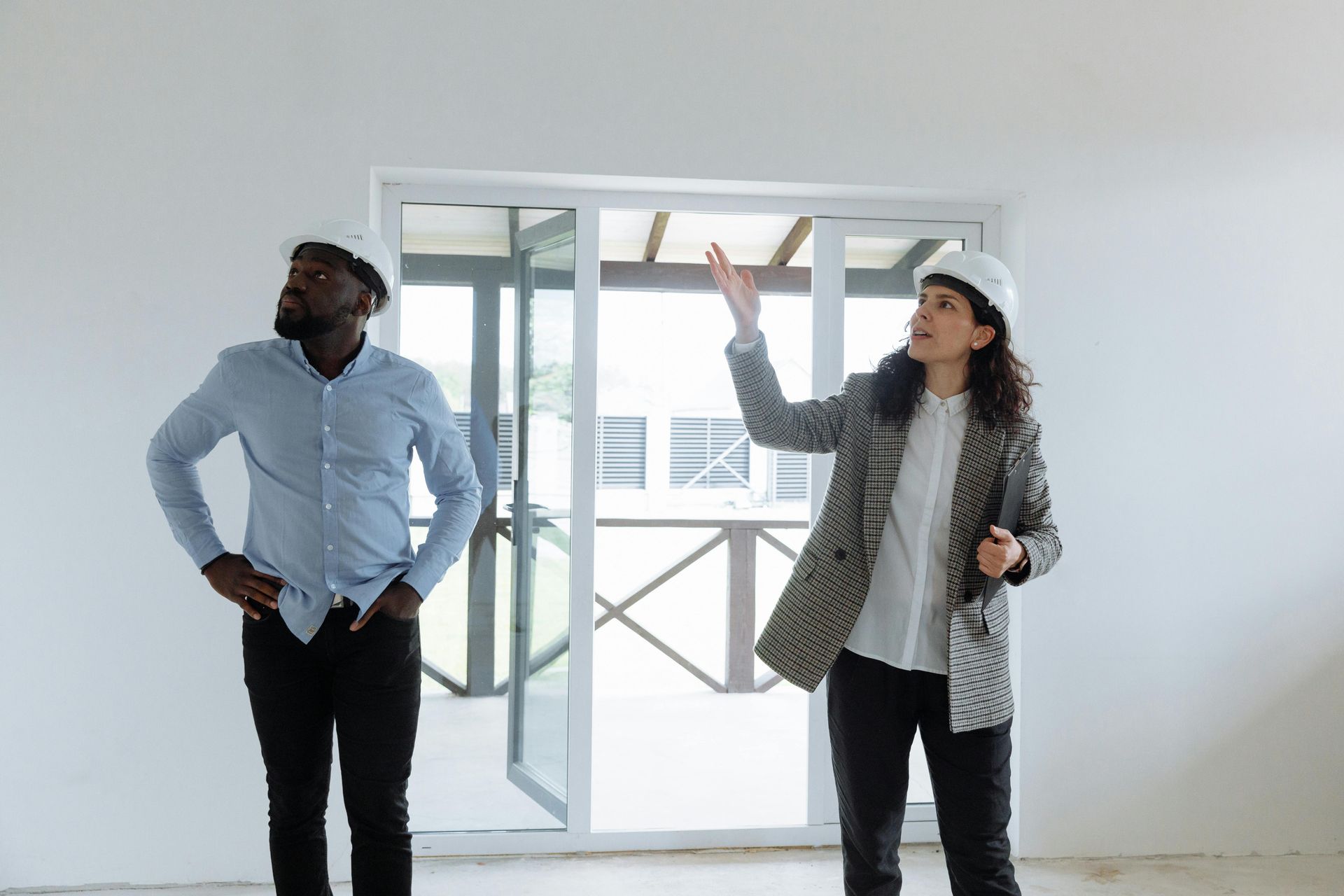 Two people in hard hats inspect a room in State College