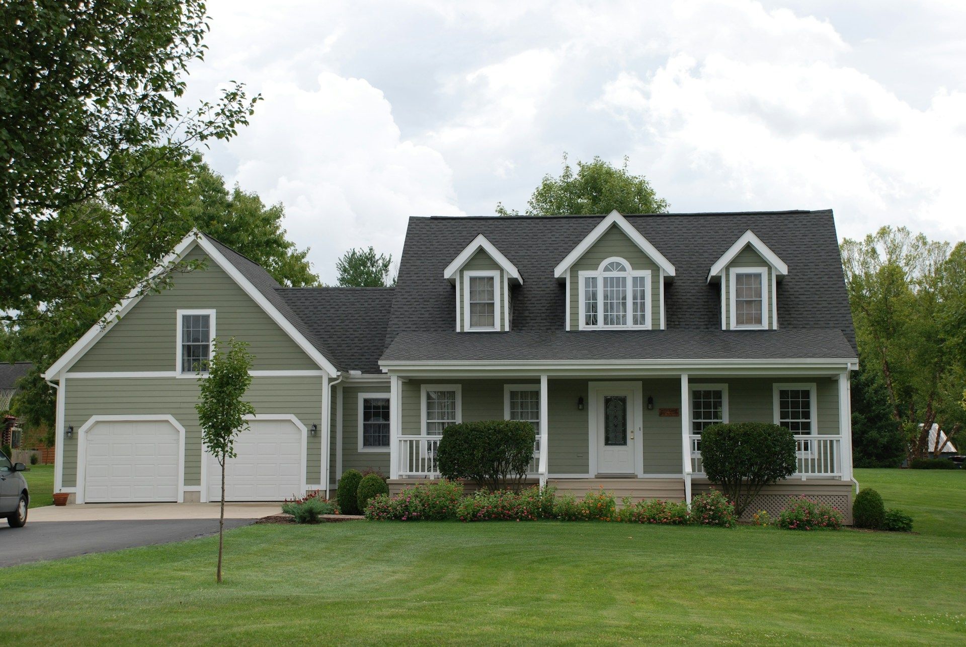 Two-story house with green siding, white trim, and a black roof; a porch in State College.