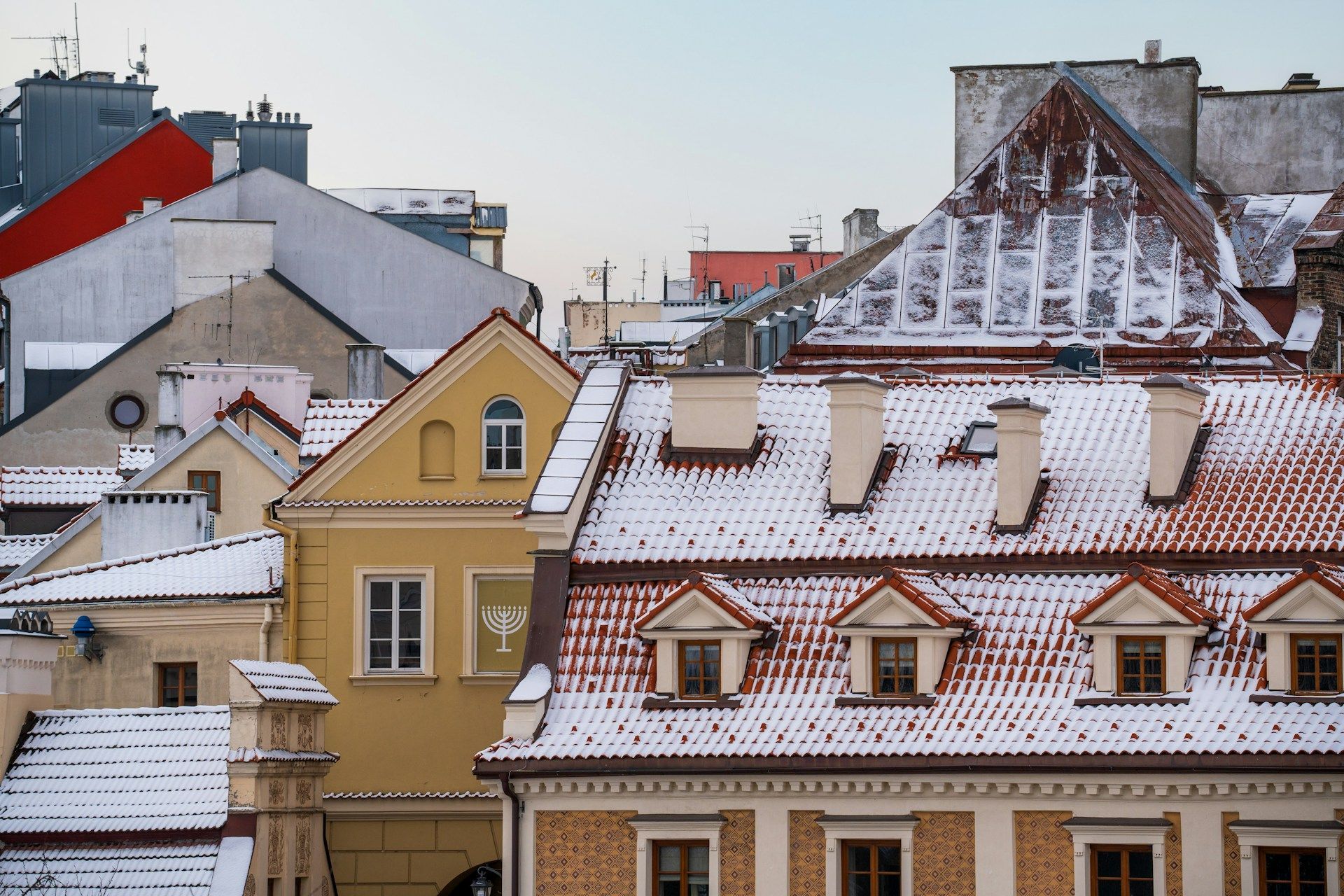 Roofs of buildings covered in snow; reddish-brown tile, yellow, and gray facades in Central PA.