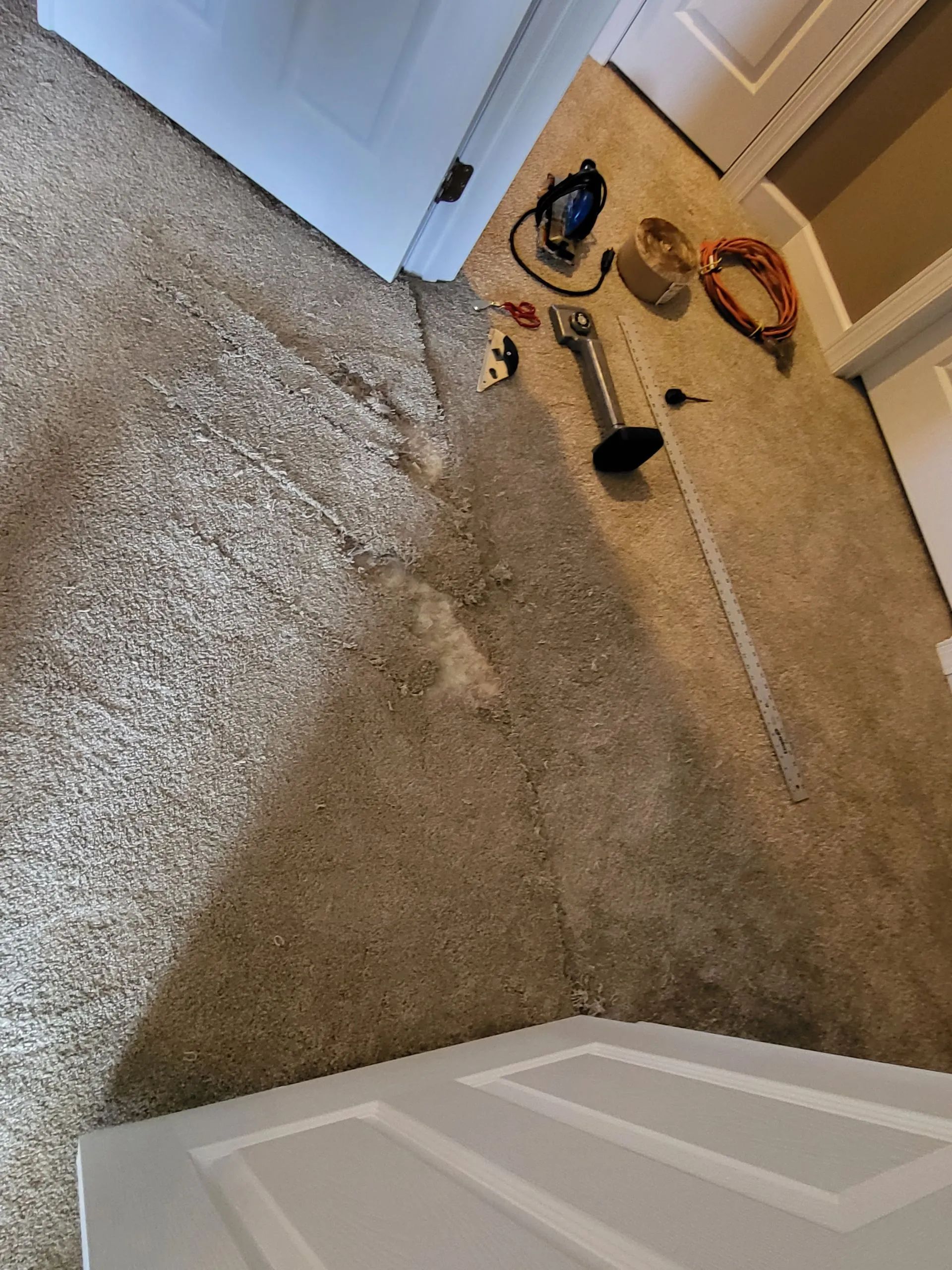 Carpeted doorway with tools, including a nail gun, visible on the floor.