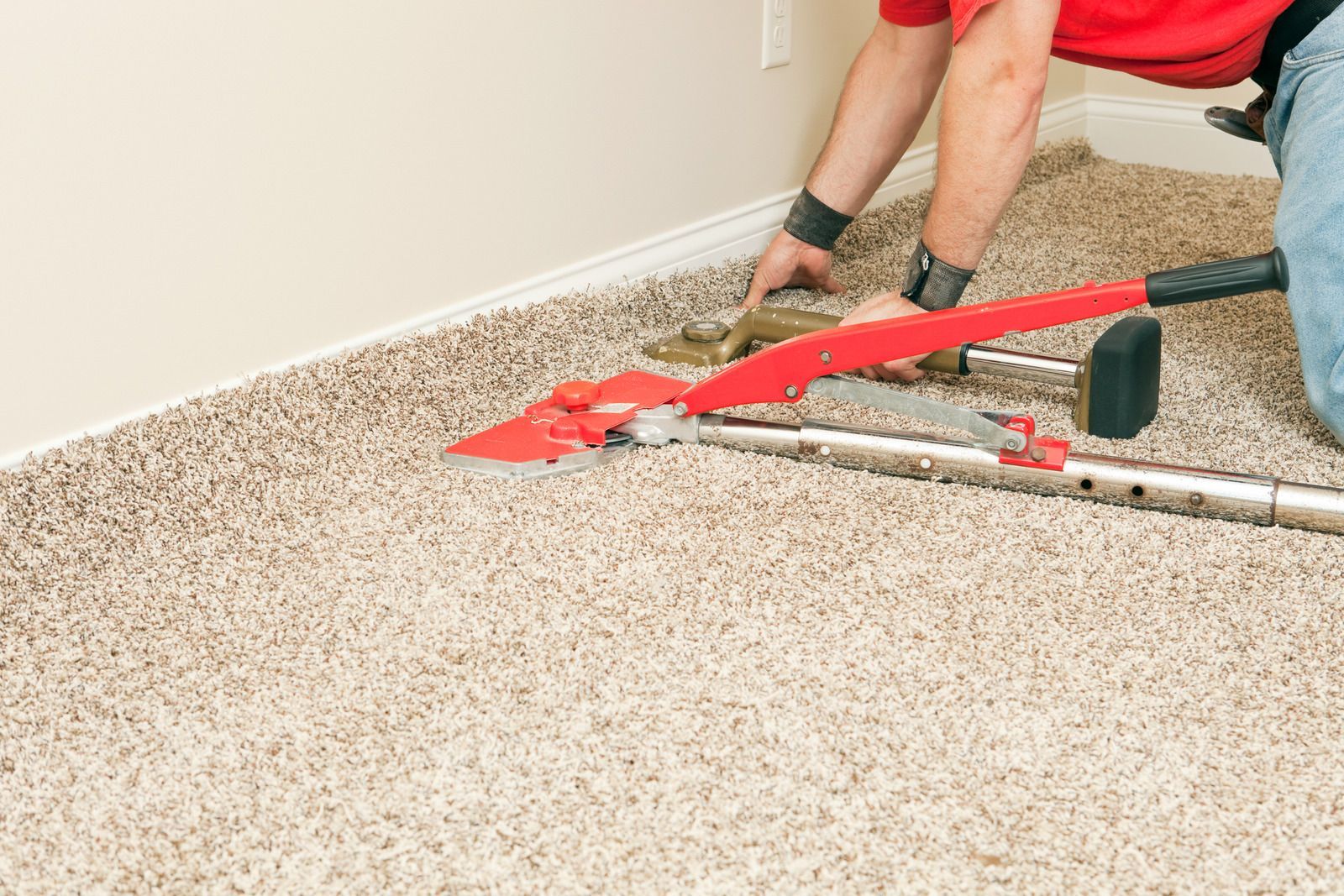 A man is cutting a piece of carpet with a pair of scissors.