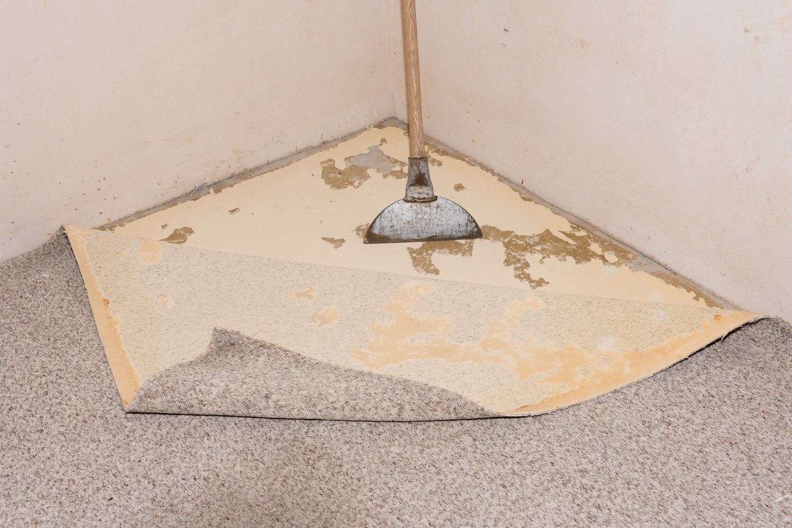 A broom is sitting on a piece of carpet in a corner of a room.