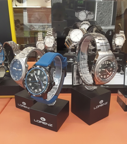 Orologi esposti su supporti neri in una vetrina. Sono visibili diversi orologi, alcuni con cinturini in metallo, uno con cinturino blu.