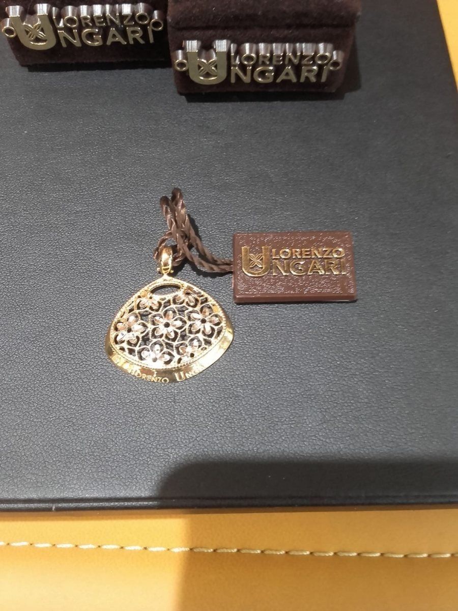 Ciondolo in oro con intarsio decorato e targhetta in pelle marrone di Ungaro.