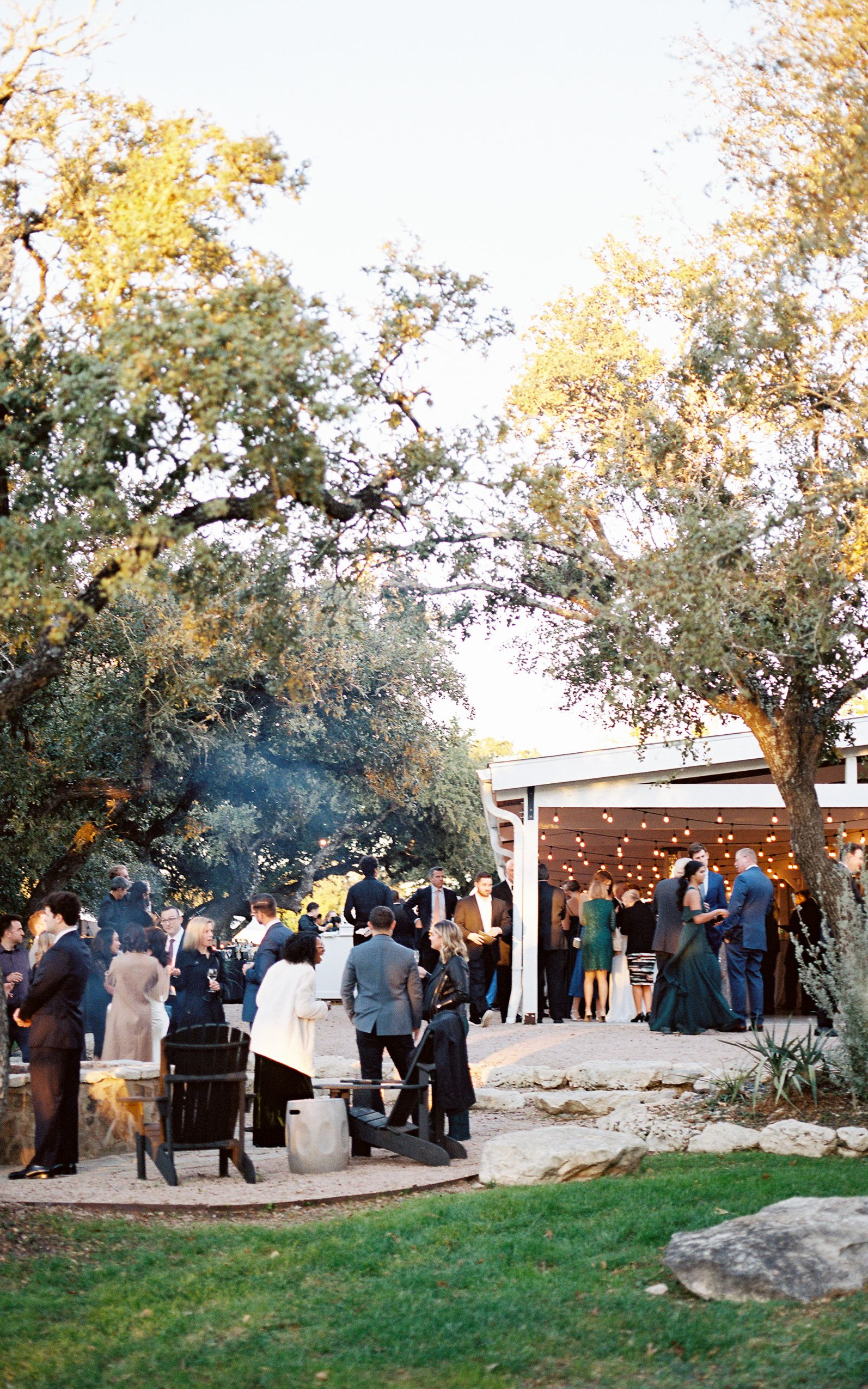 Outdoor evening event with guests, trees, and a lit structure at The Addison Grove. 
