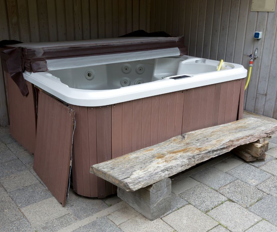 A hot tub is sitting on a patio next to a wooden bench.