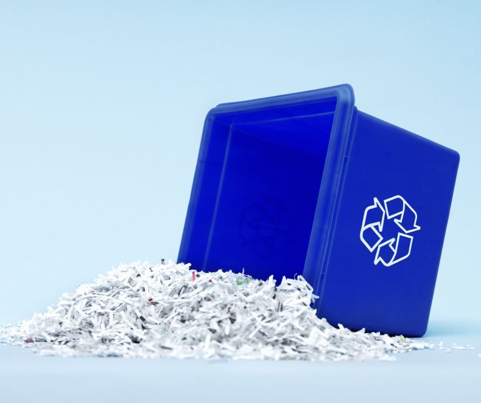 A blue recycling bin filled with shredded paper