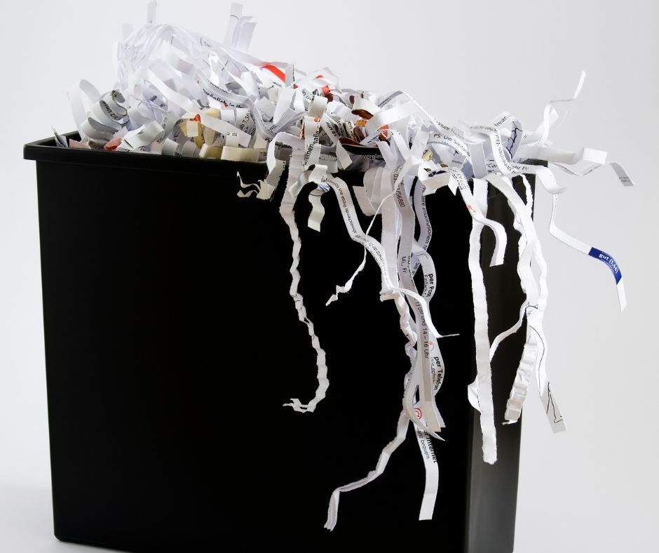 A black bin filled with shredded paper on a white background